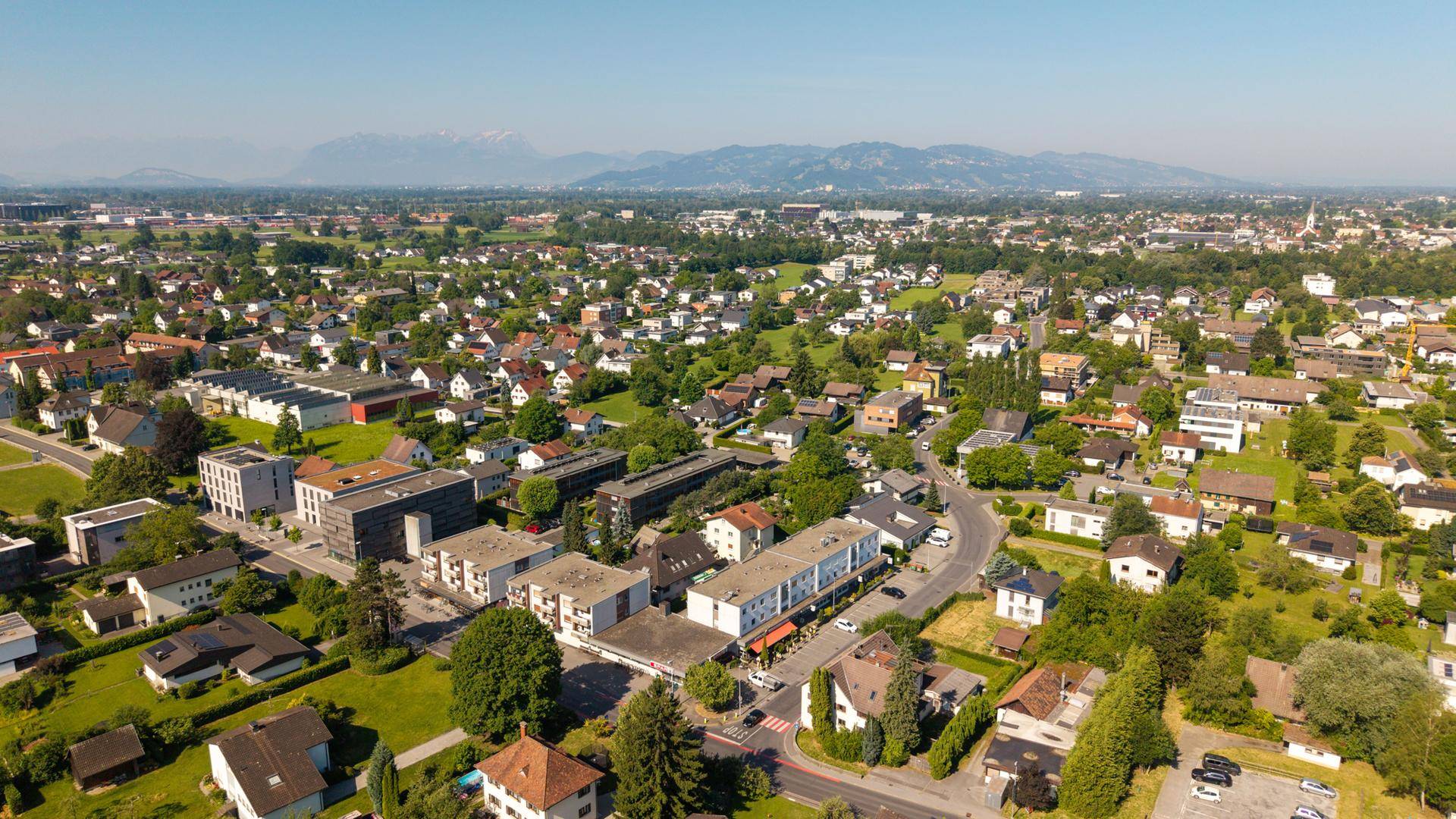 Weitläufige Luftaufnahme einer Stadt mit Wohngebieten und Bergen am fernen Horizont.