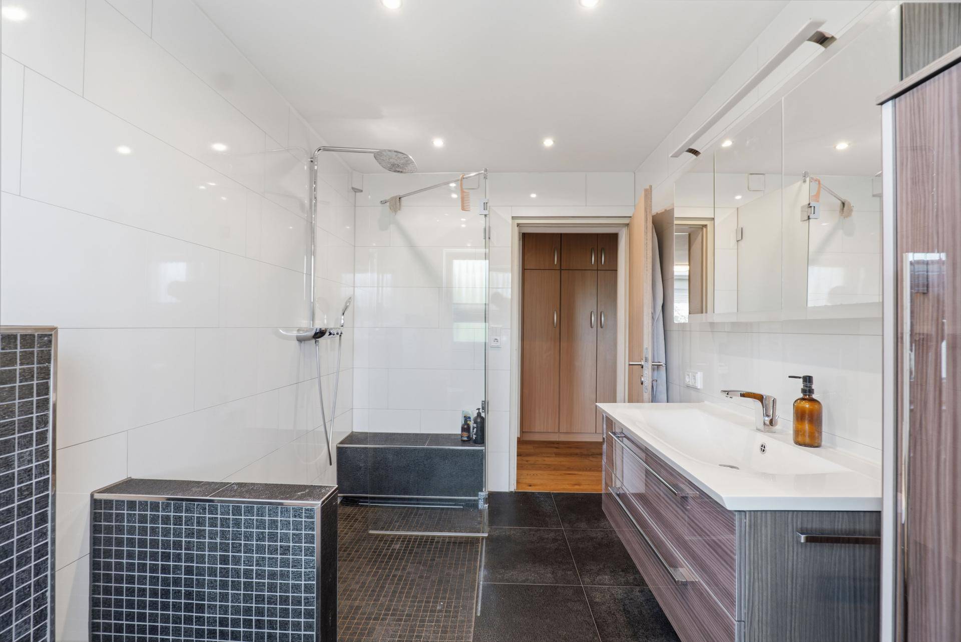 Geräumiges Badezimmer mit großer Dusche, Doppelwaschbecken und Spiegelschrank.