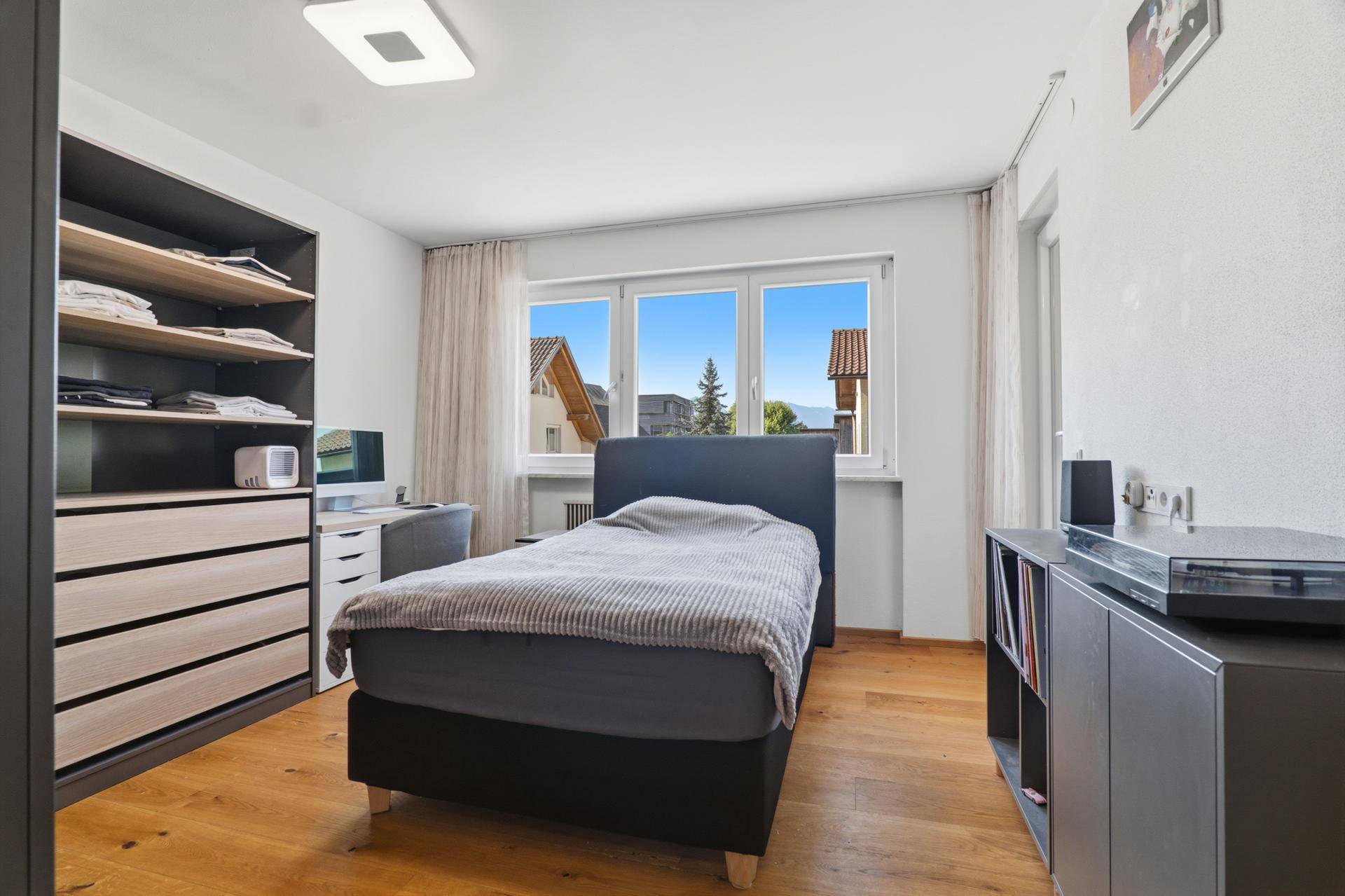 Schlafzimmer mit Holzboden, Einzelbett und integriertem Kleiderschrank.