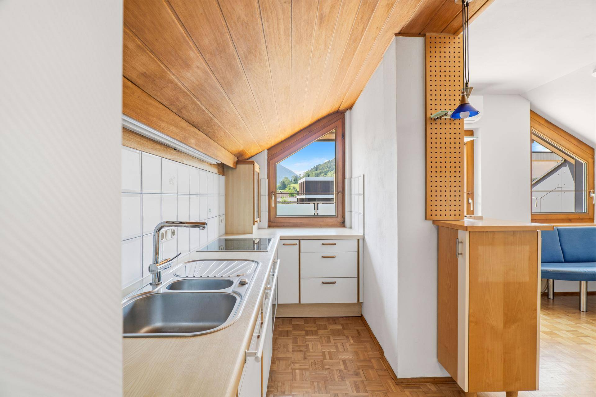 Helle Küche mit Spülbecken, Kochfeld und Fenster mit Bergblick.
