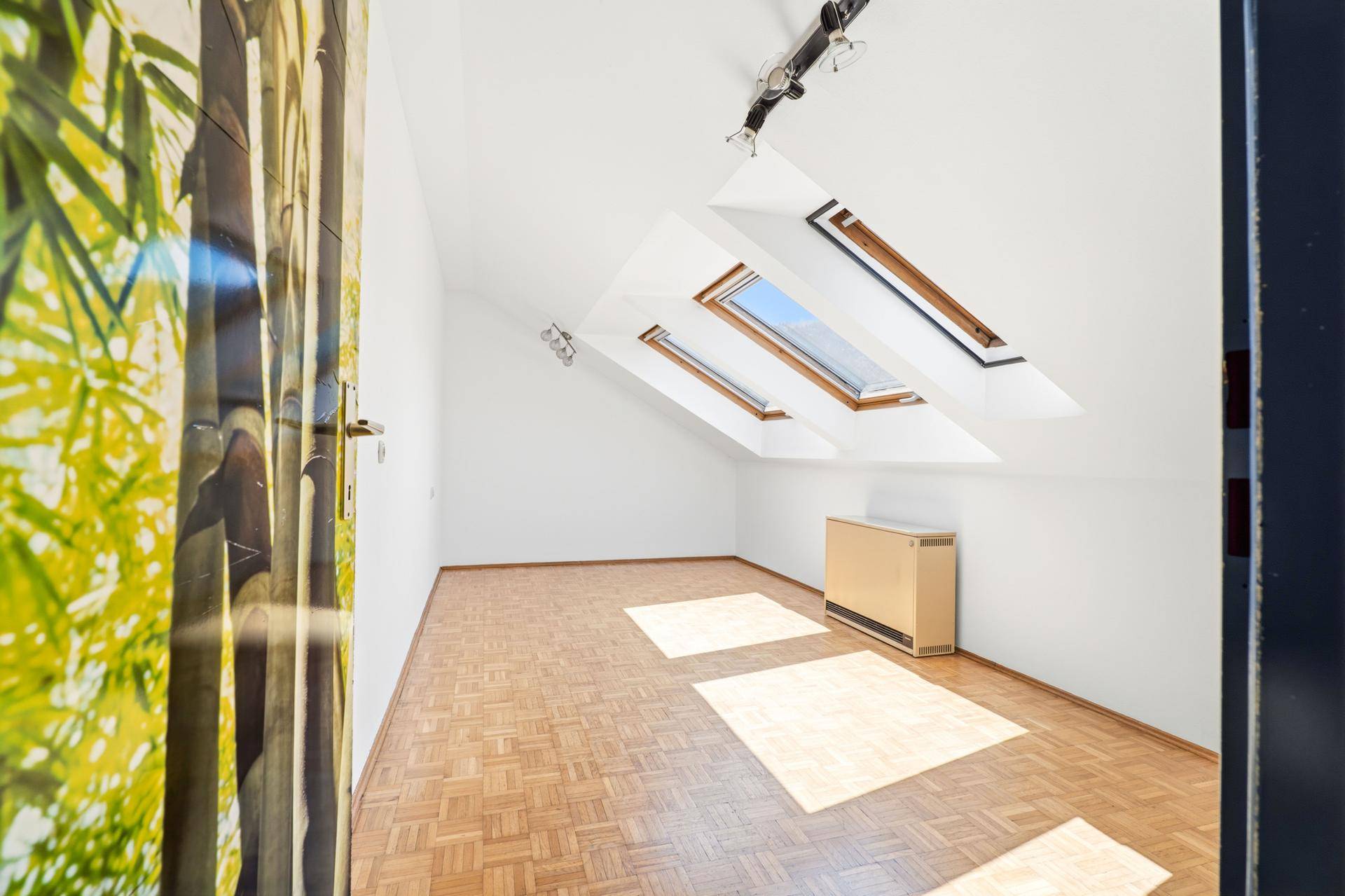 Helles Schlafzimmer mit Dachfenstern, Holzboden und viel natürlichem Licht.