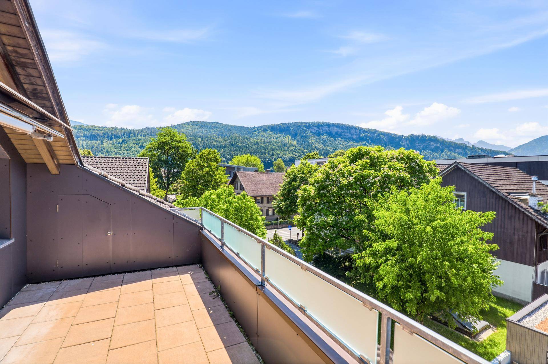 Helle Dachterrasse mit Blick auf grüne Bäume und die Nachbarschaft.