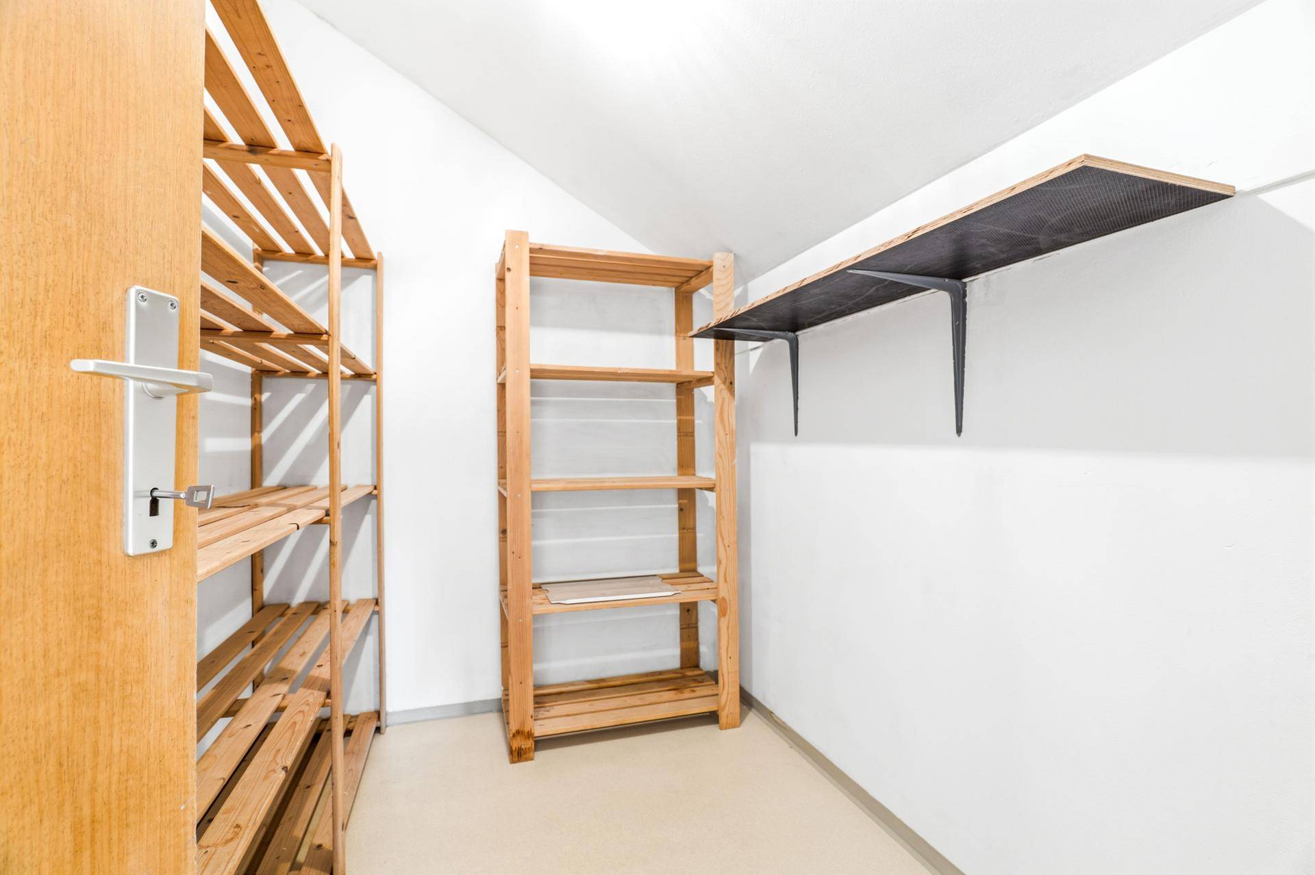 Praktischer Abstellraum mit Holzregalen für zusätzlichen Stauraum und Organisation.