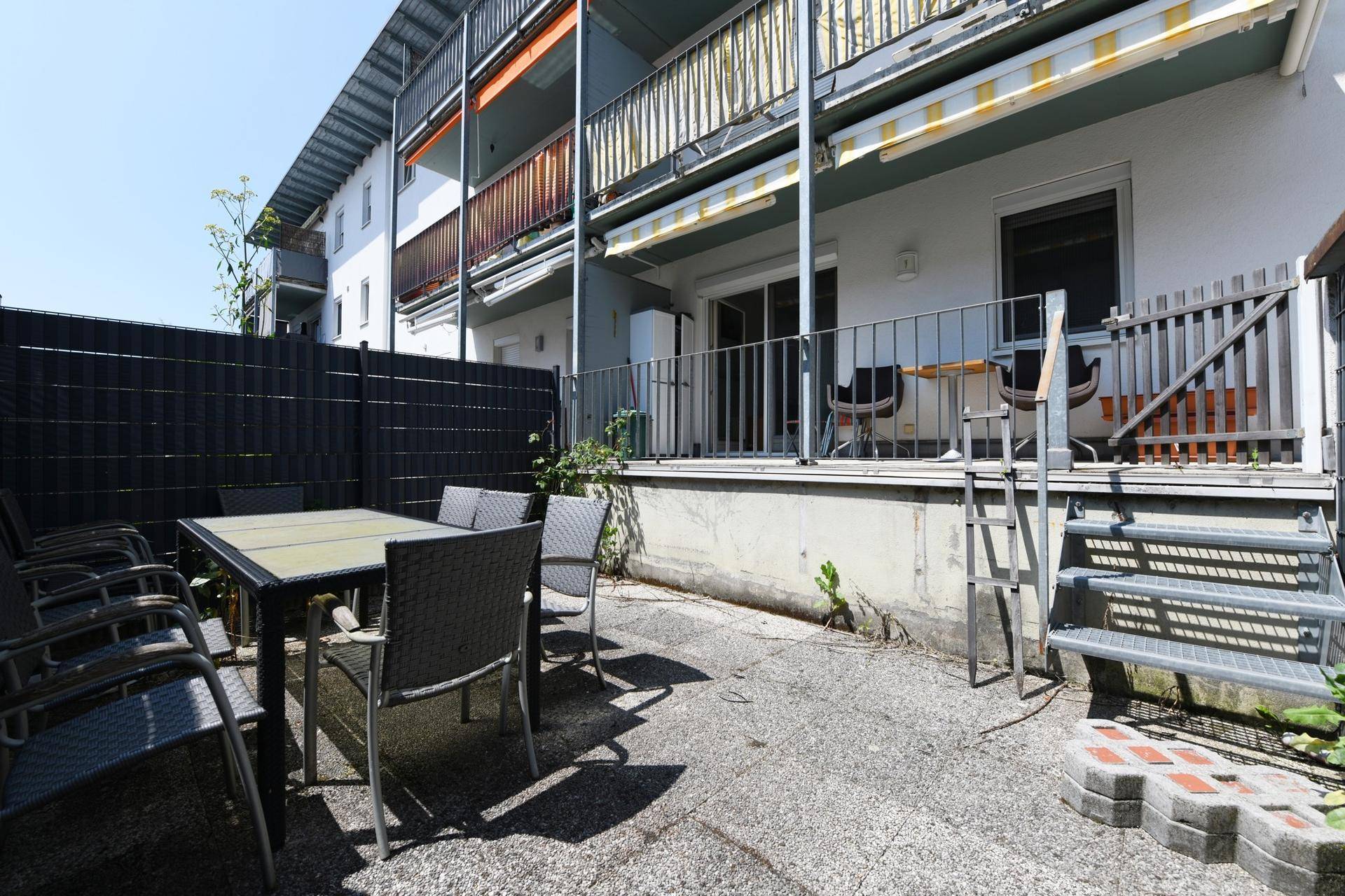 Geräumige Terrasse mit Gartenmöbeln und Treppe zum oberen Balkonbereich.