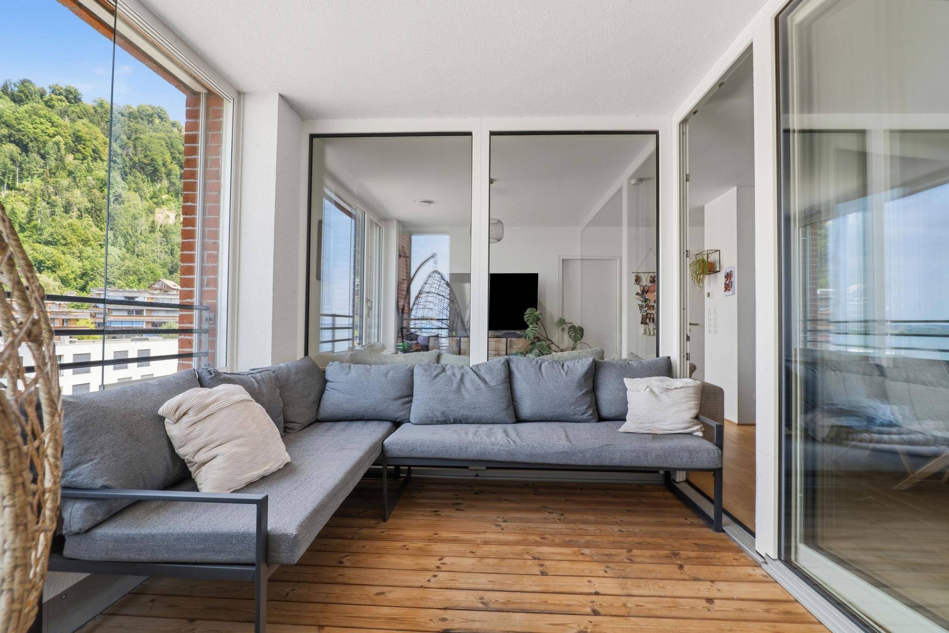 Geräumiger verglaster Balkon mit bequemen Sitzmöbeln und weitem Blick auf die Umgebung.