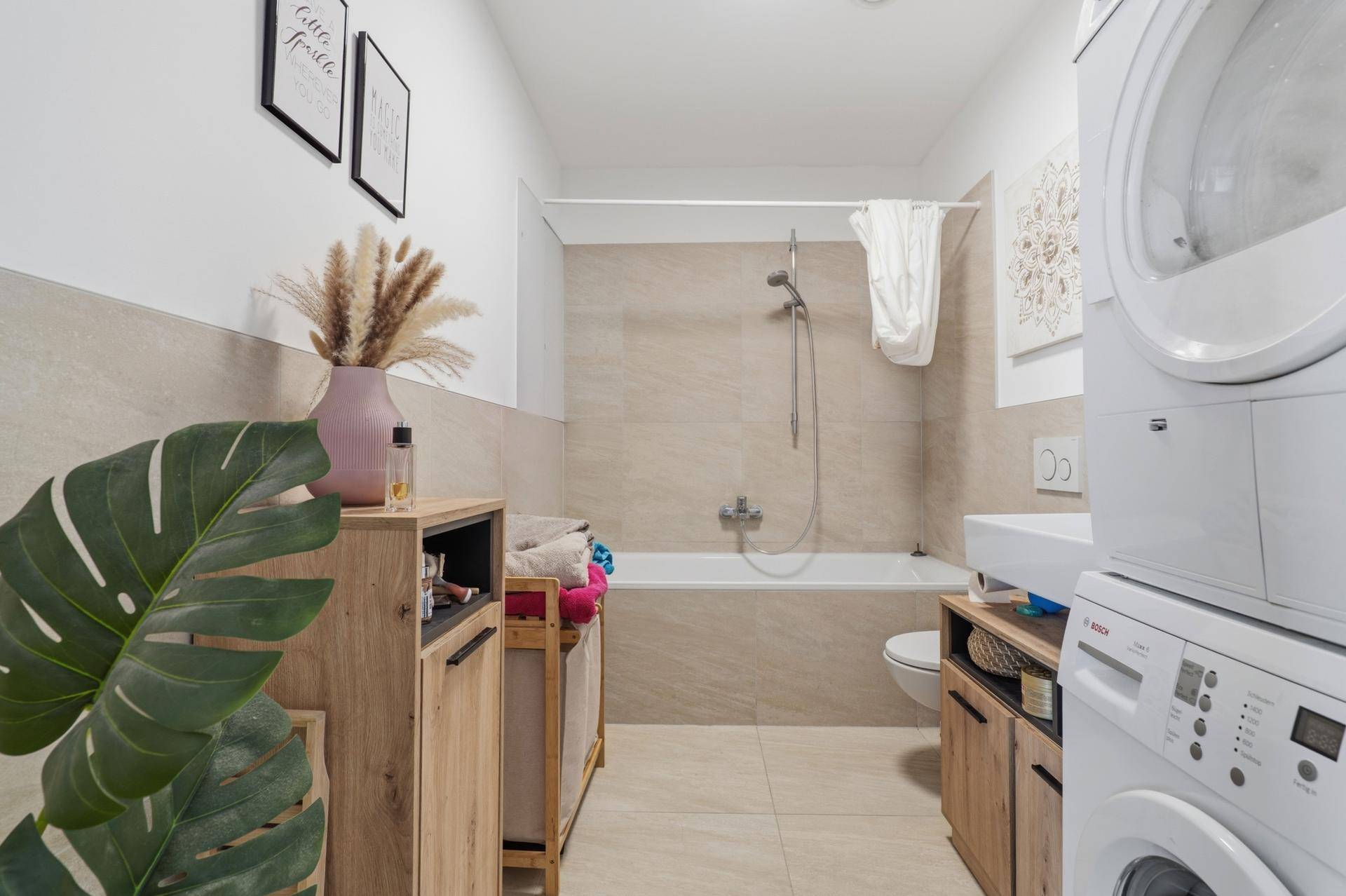 Modernes Badezimmer mit Badewanne, Waschbecken und integrierter Waschmaschine und Trockner.