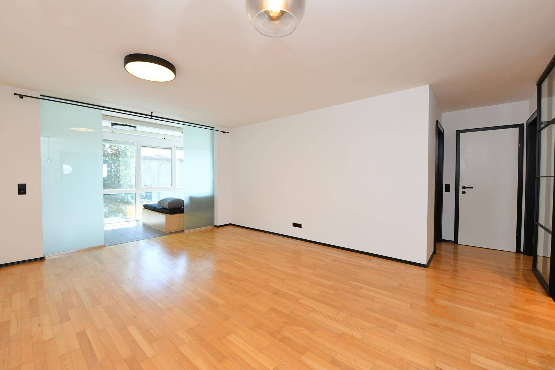 Heller Wohn-Essbereich mit Holzboden und Zugang zum Wintergarten, bereit zur individuellen Gestaltung.