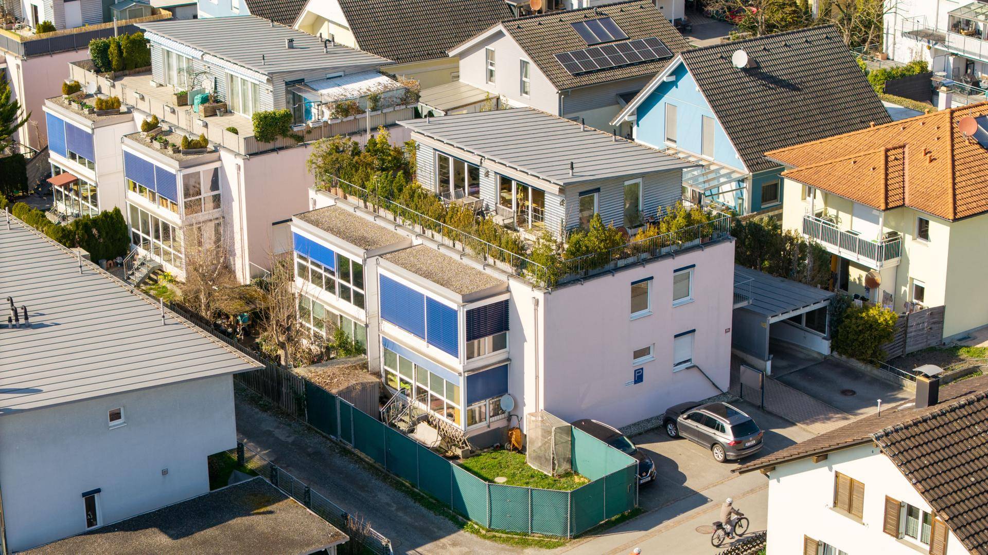 Luftaufnahme des Gebäudes mit begrüntem Flachdach und umliegenden Häusern.