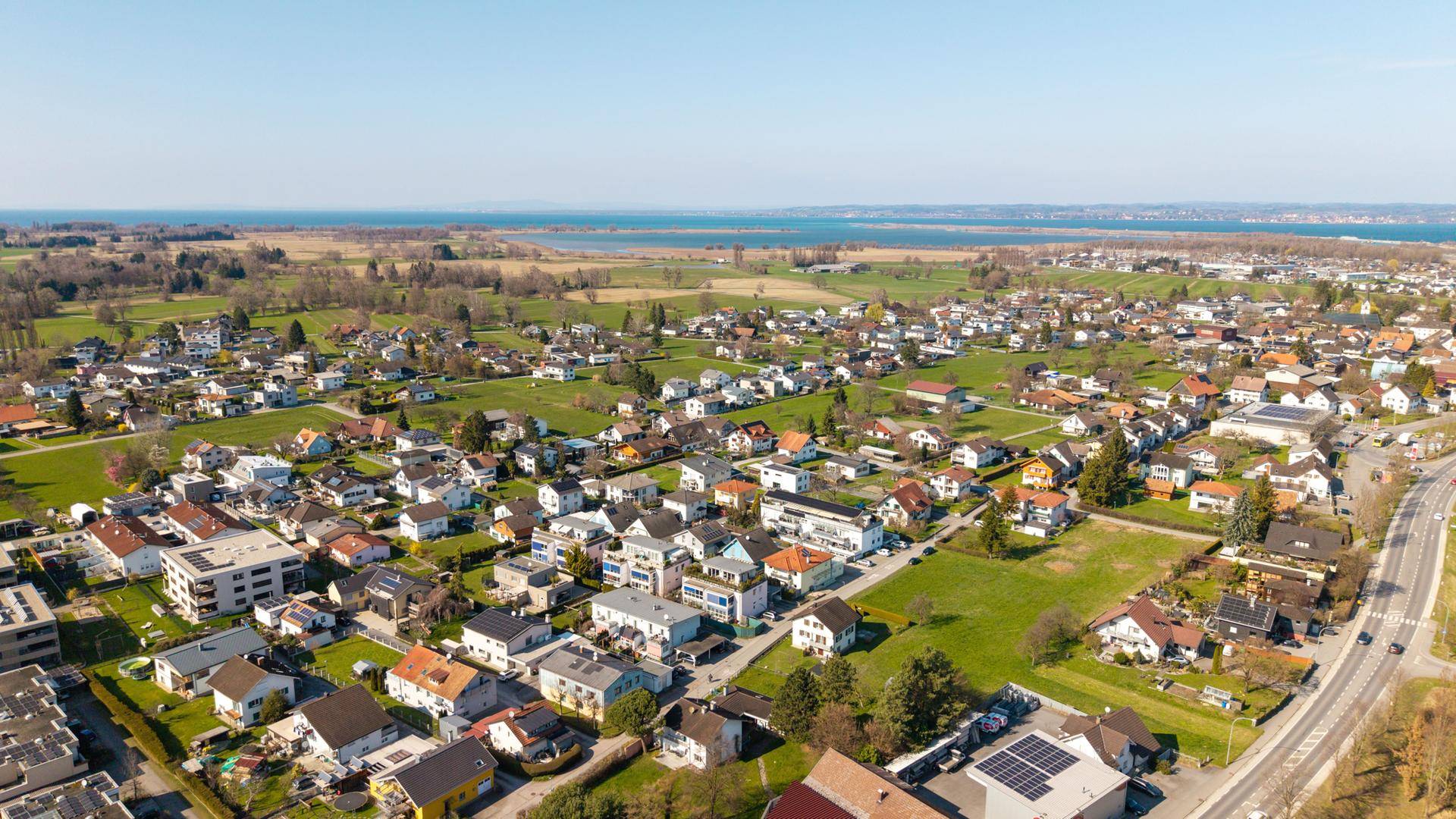 Panoramablick aus der Luft auf die Wohnsiedlung mit See im Hintergrund.