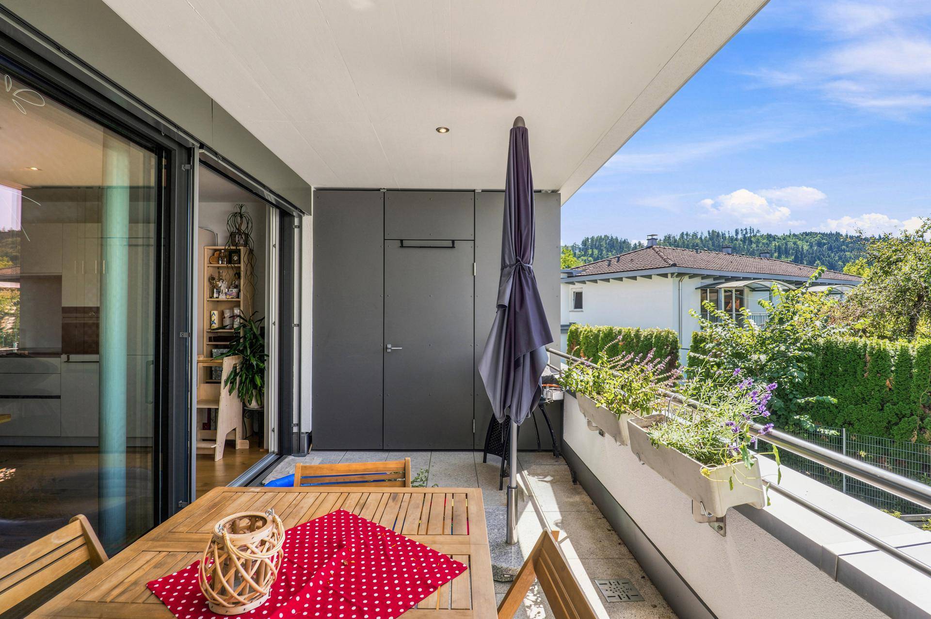 Balkon mit Esstisch, Sonnenschirm und Blick auf die umliegende Landschaft.