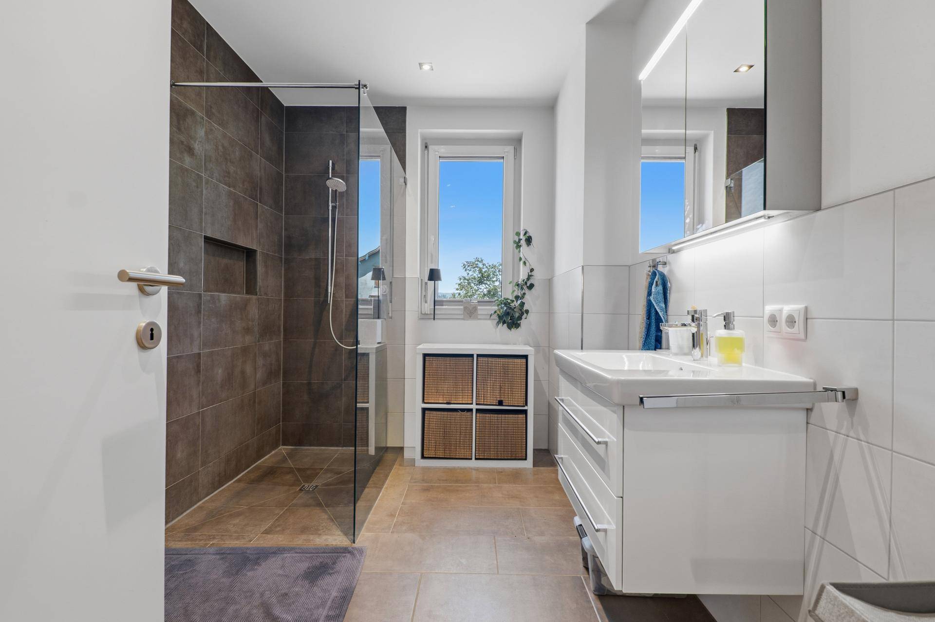Modernes Badezimmer mit begehbarer Dusche, Waschtisch und Fenster.