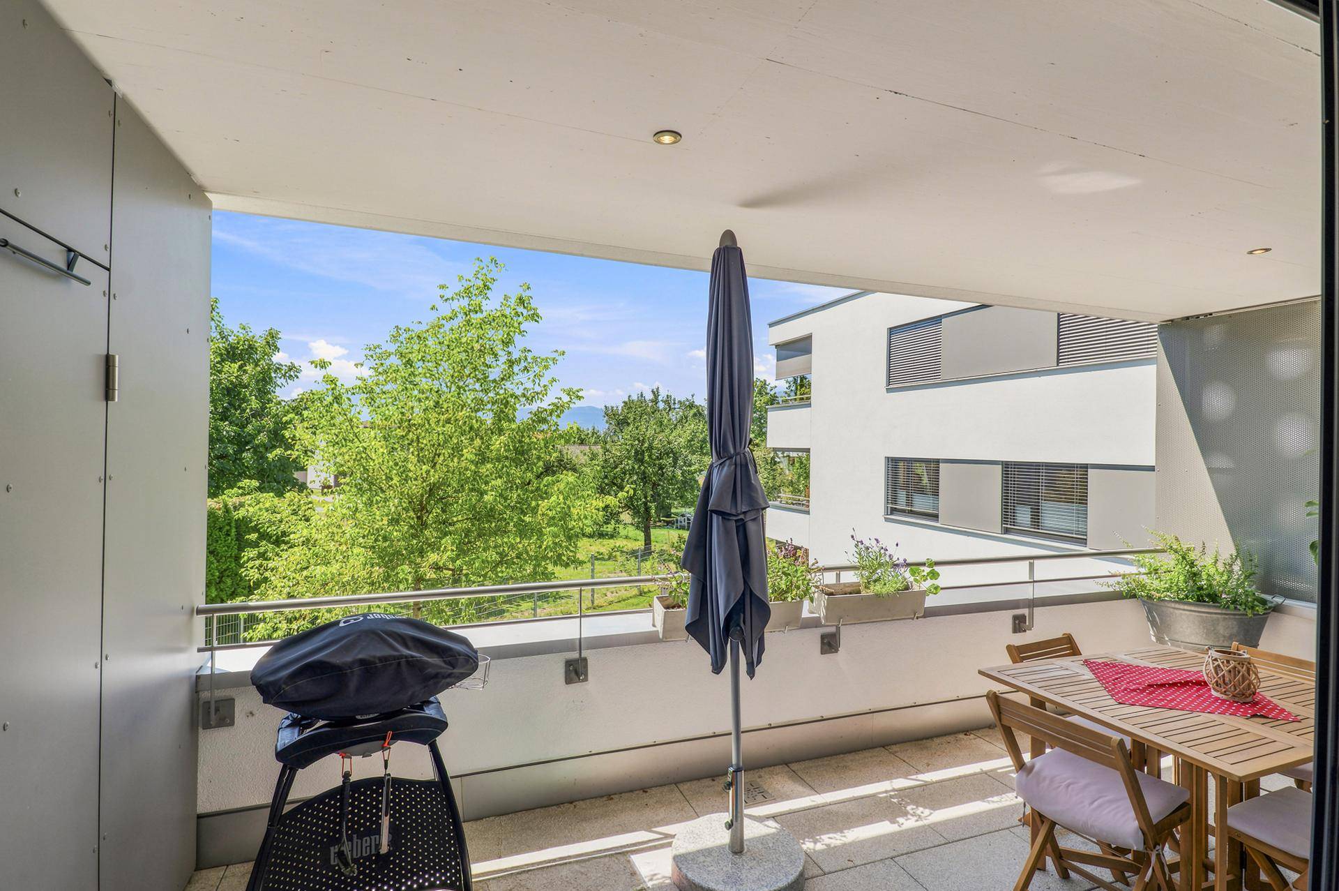 Geräumiger Balkon mit Esstisch, Grill und Blick ins Grüne.
