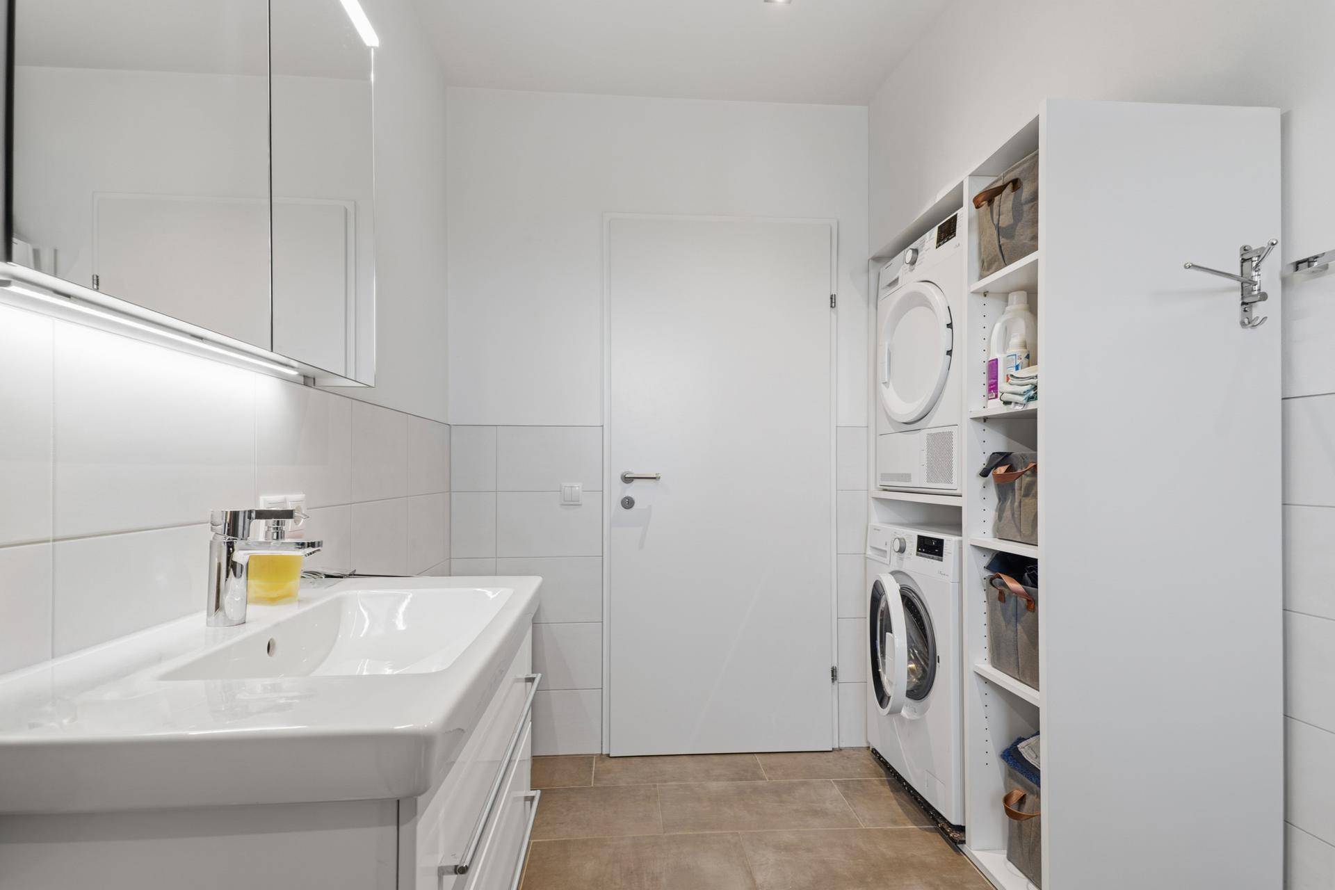 Badezimmer mit Waschmaschine, Trockner und Waschtisch.