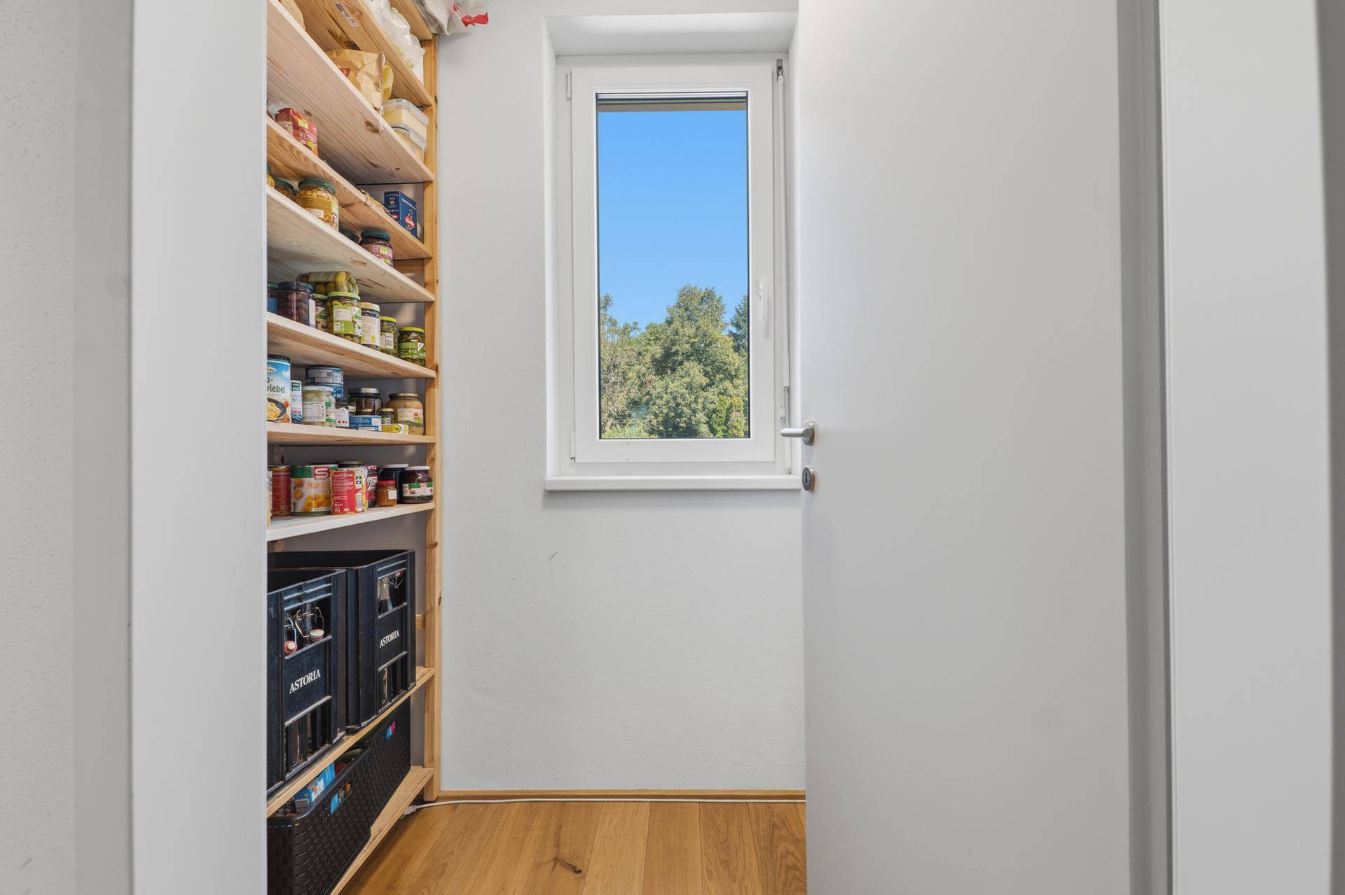 Praktische Speisekammer mit Regalen, gefüllt mit Vorräten und einem Fenster.