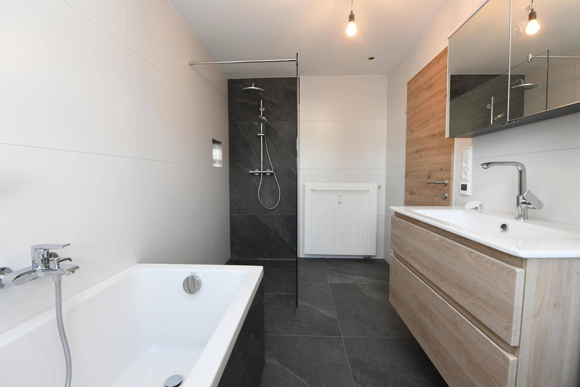 Zeitgemäßes Badezimmer mit Badewanne, Dusche und Waschtisch, ausgestattet mit modernen Armaturen.