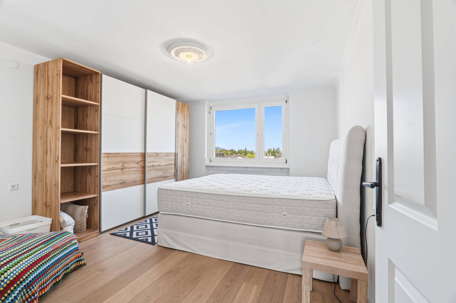 Helles Schlafzimmer mit Doppelbett, Holzboden und großem Kleiderschrank.