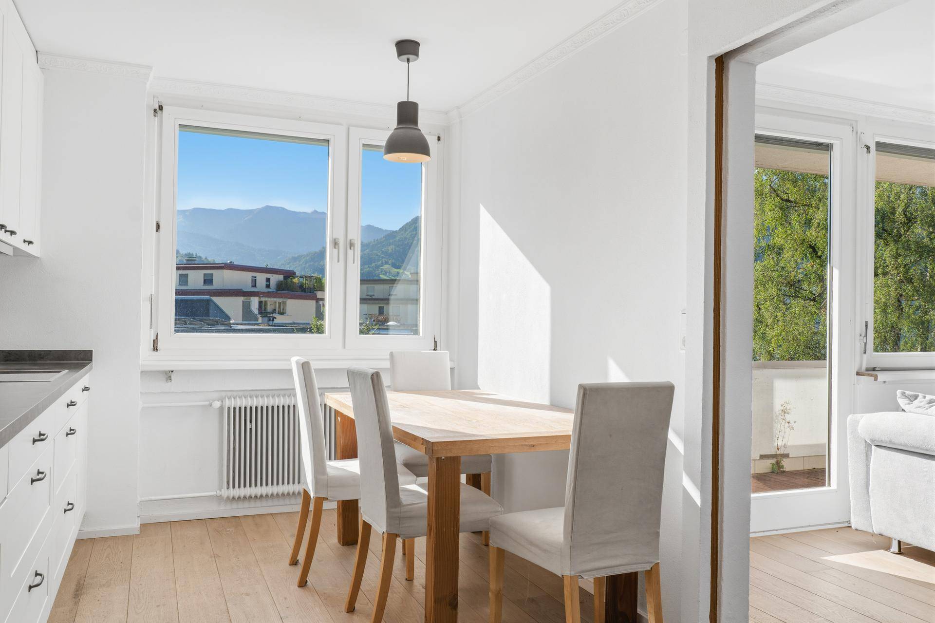 Helle Küche mit Essbereich, Holzboden und Bergblick durch das Fenster.