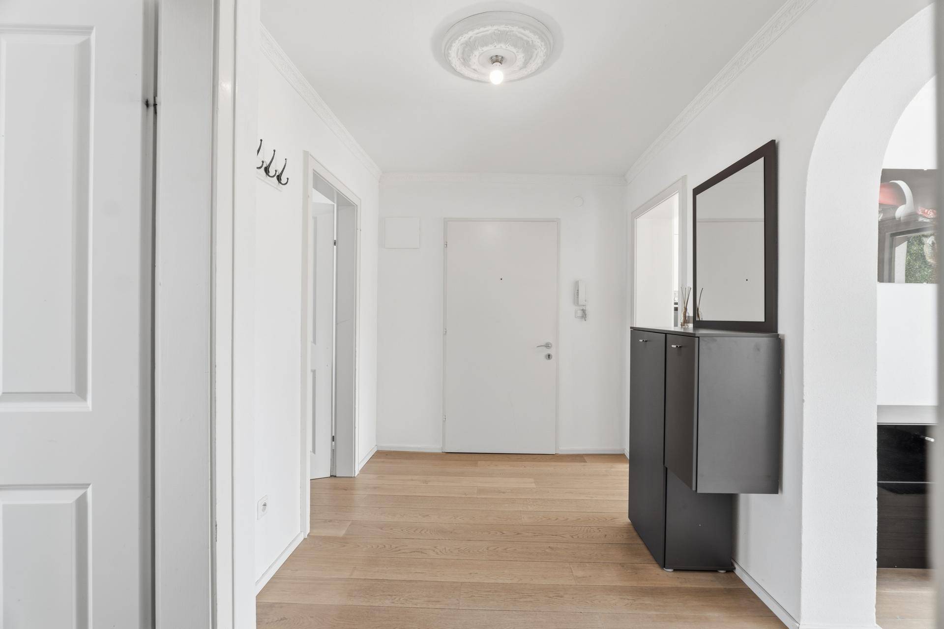 Heller Flur mit Holzboden, Garderobe und Zugang zu verschiedenen Räumen.