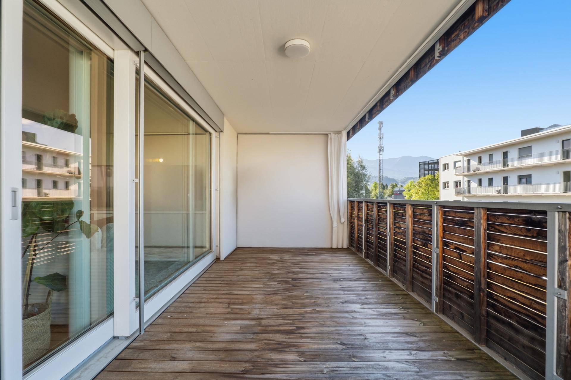 Langer Balkon mit Holzboden und seitlichem Blick auf die Berge.