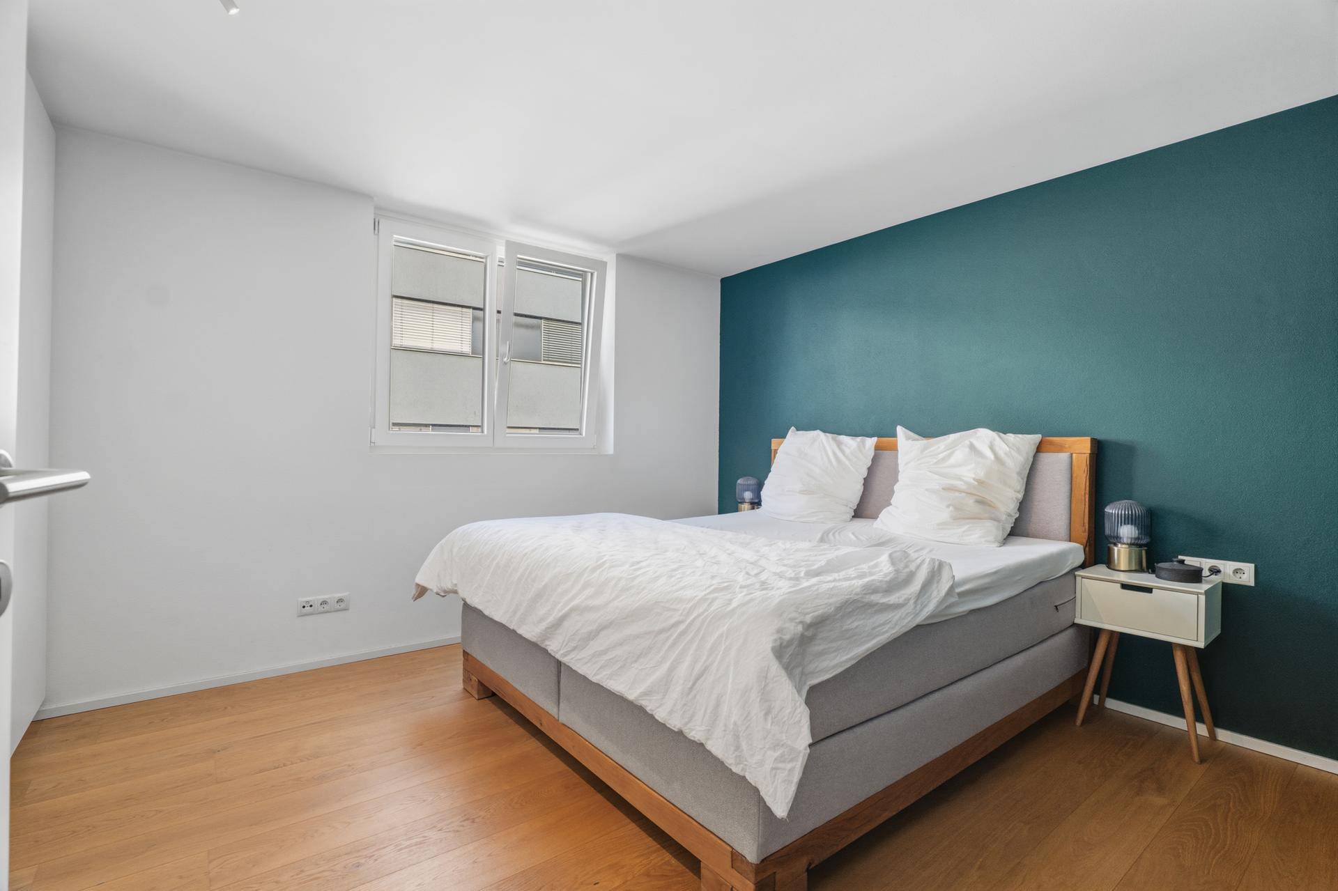 Schlafzimmer mit Doppelbett, Fenster und grüner Wand.