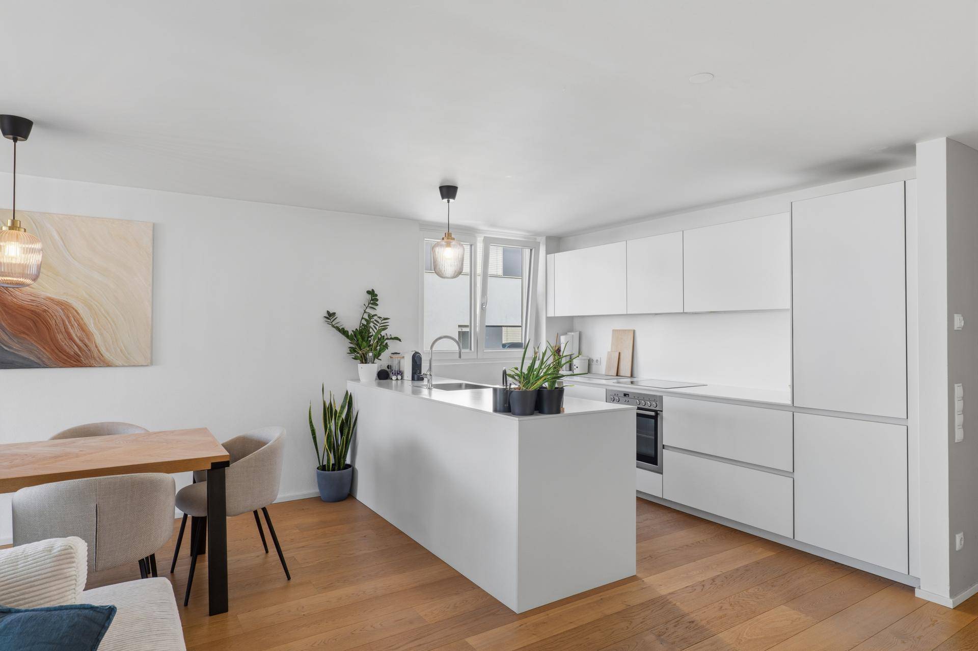 Moderne, weiße Einbauküche mit Kochinsel und viel Arbeitsfläche.