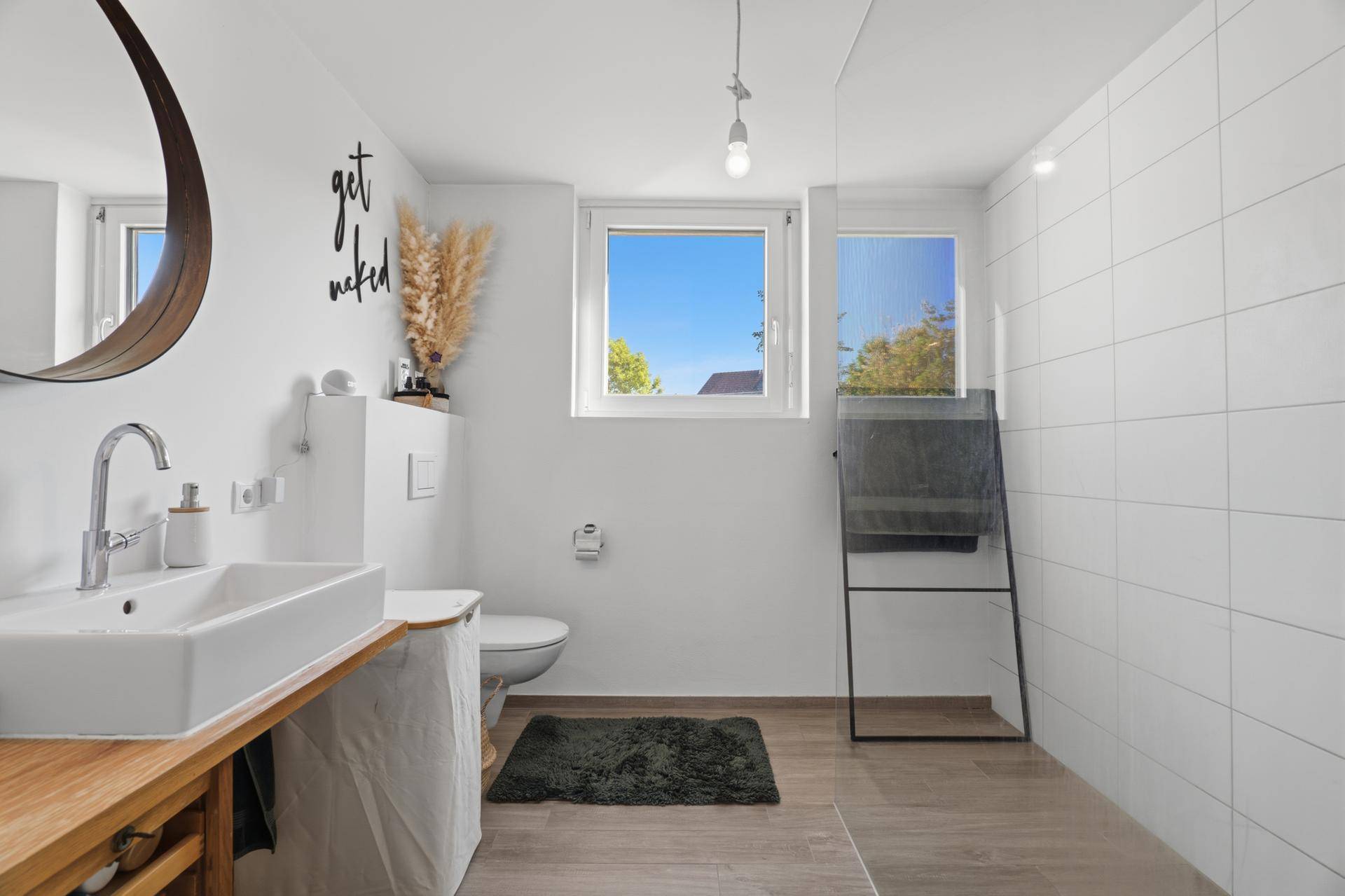 Helles Badezimmer mit ebenerdiger Dusche, Fenster und modernem Design.