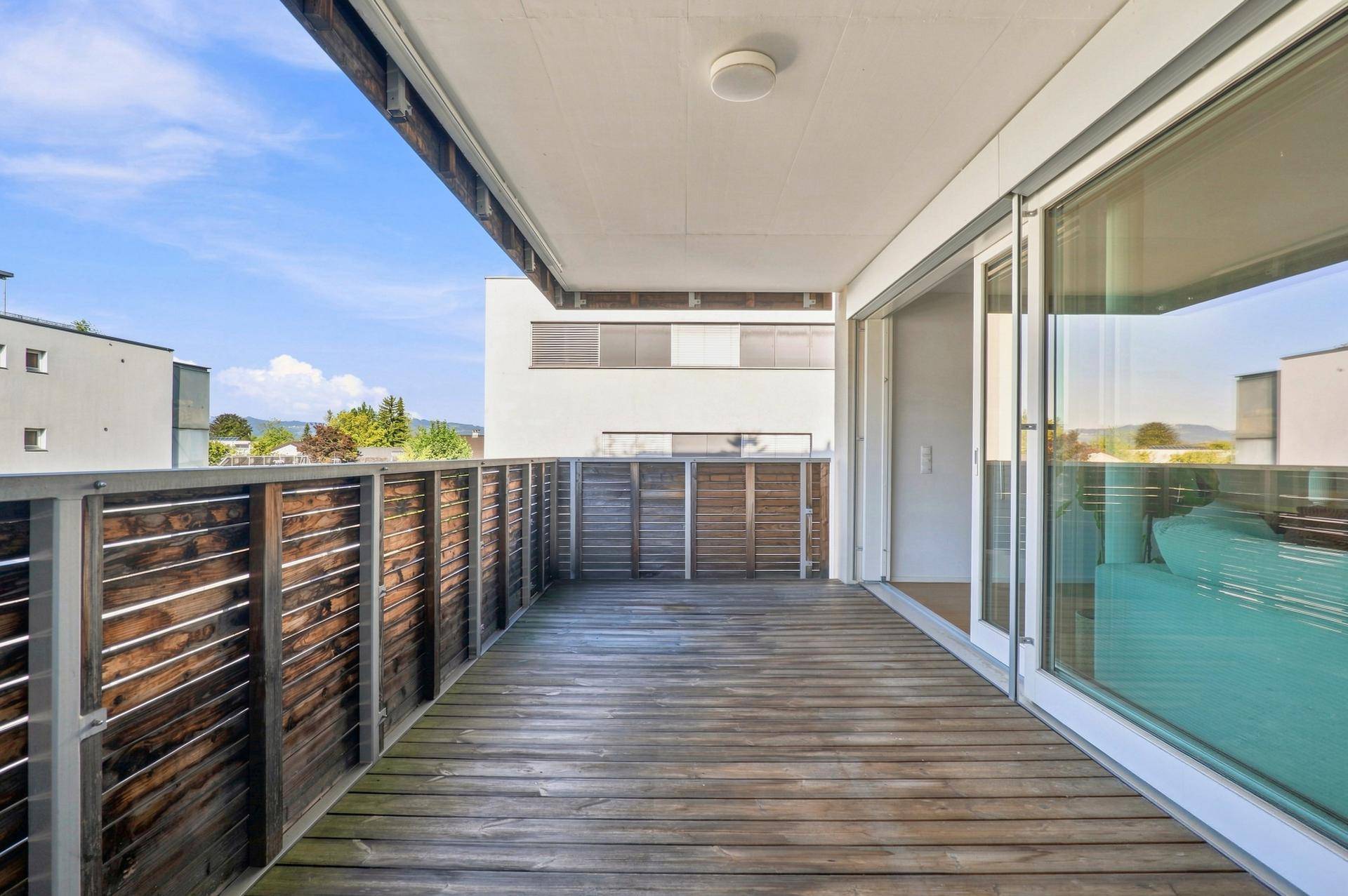 Geräumiger Balkon mit Holzboden und Blick auf die Umgebung.