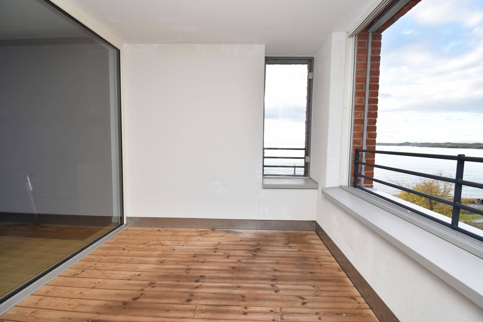 Heller Balkon mit Holzboden und weitem Blick auf den See und die Umgebung.
