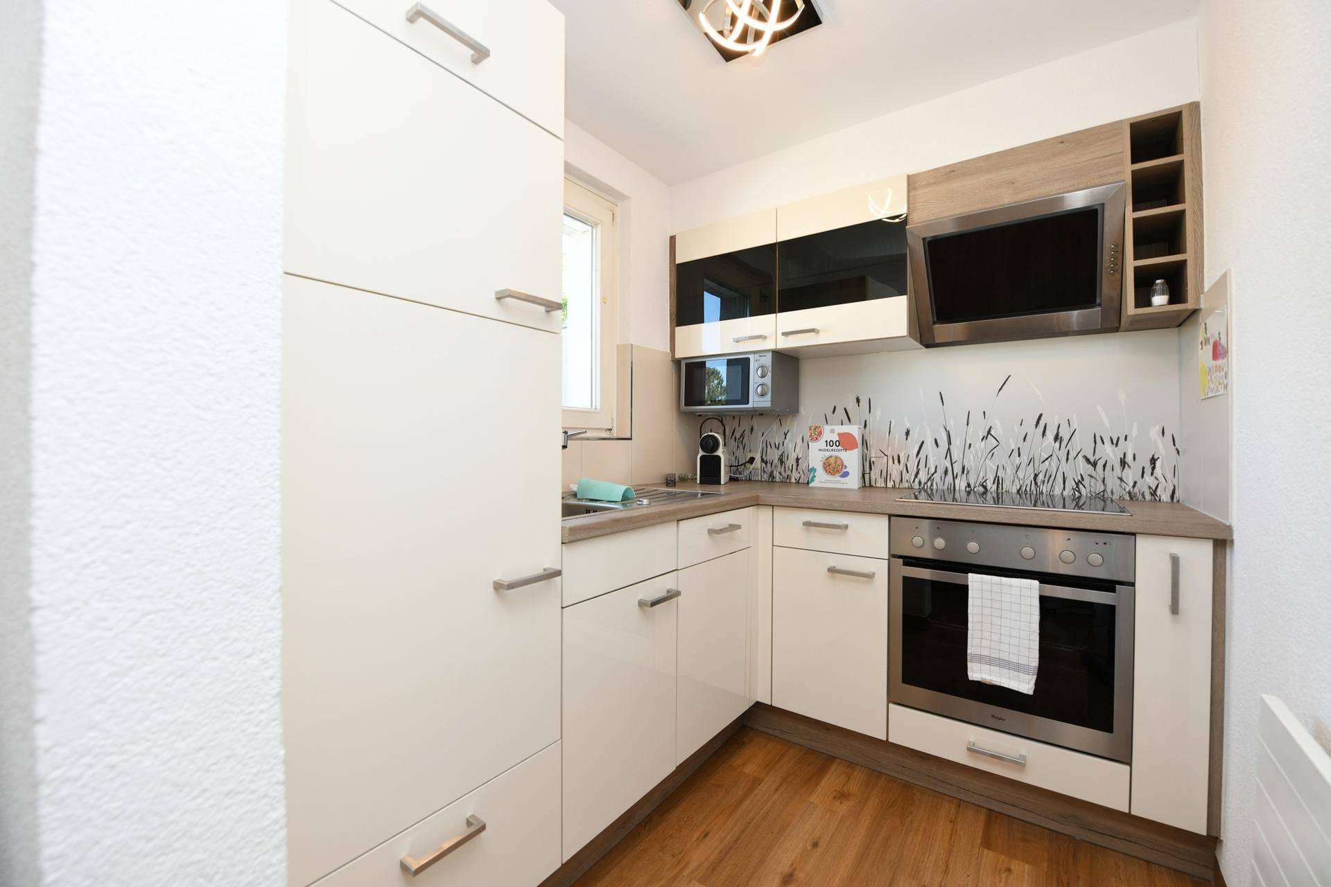 Moderne Einbauküche mit hellen Fronten, Backofen und Mikrowelle.