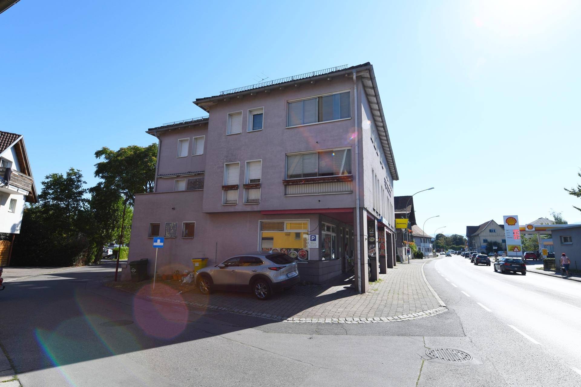 Vorderansicht des Gebäudes an einer Straße mit Geschäften im Erdgeschoss.