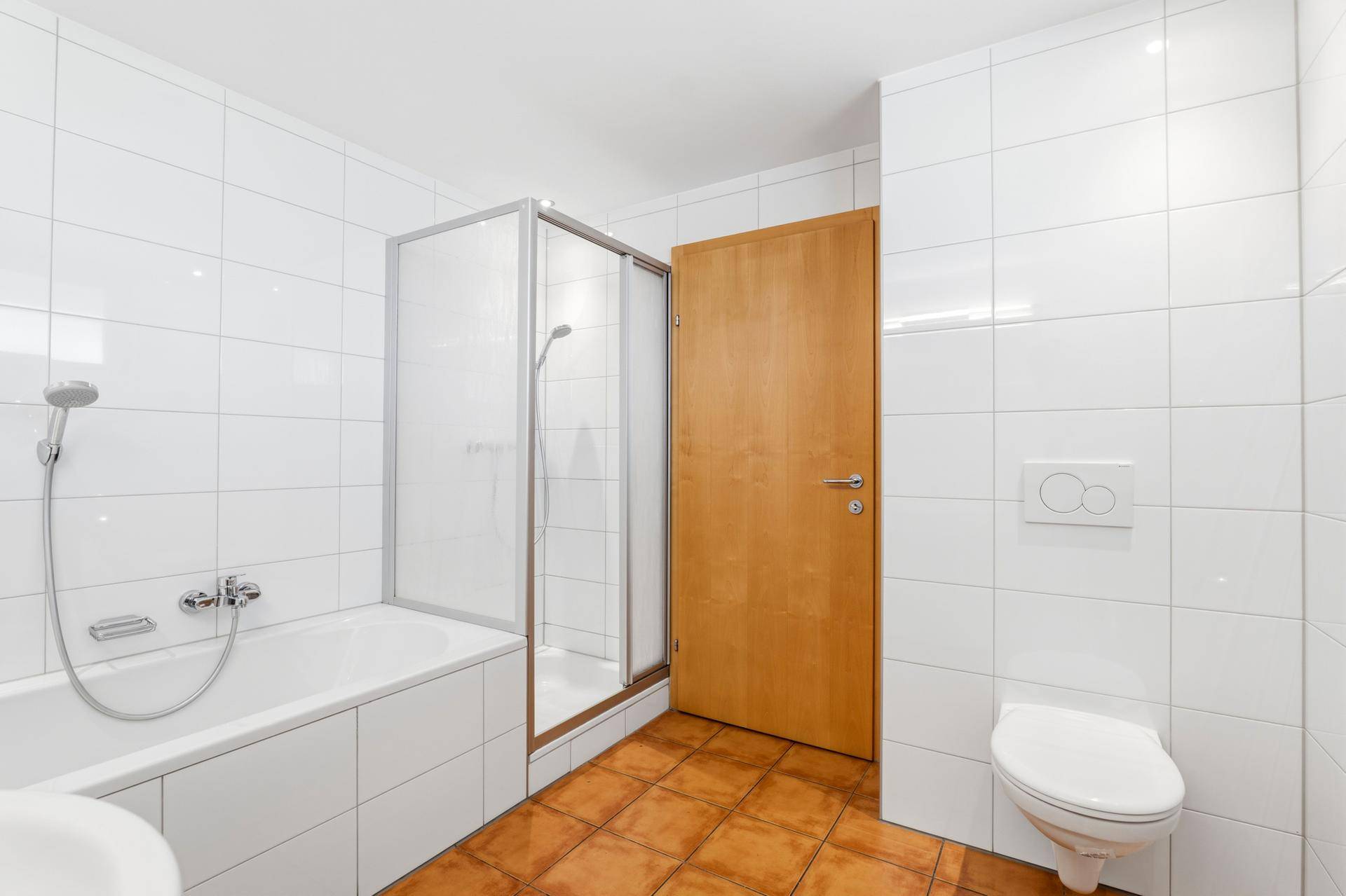 Badezimmer mit Badewanne, Duschkabine und wandhängendem WC.