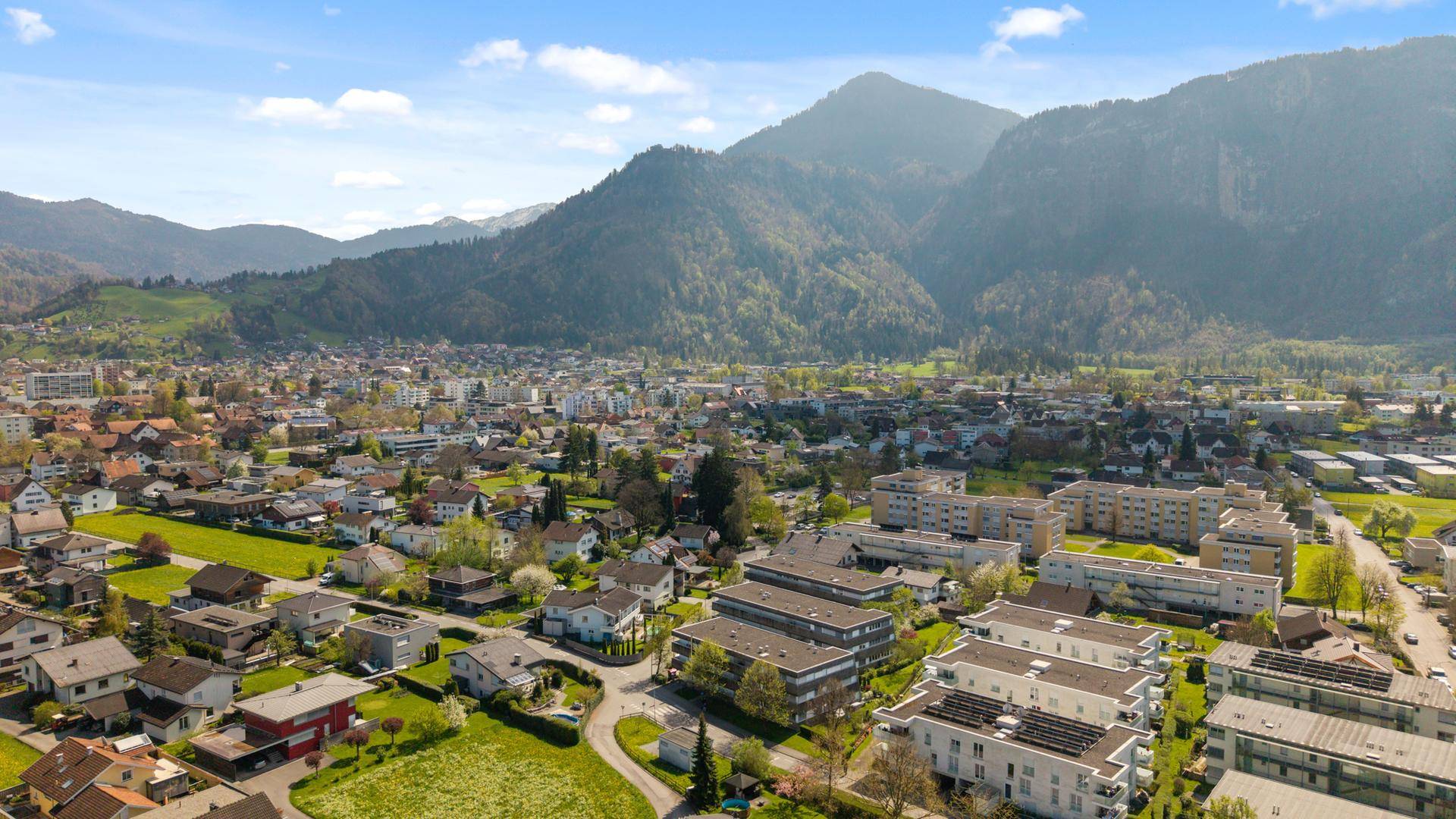 Panoramablick auf eine Stadt am Fuße majestätischer Berge unter blauem Himmel.