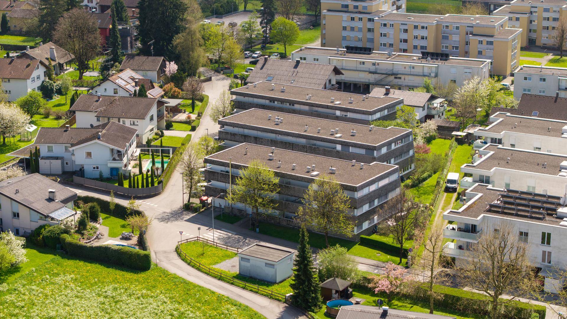 Luftaufnahme einer Wohnsiedlung mit Mehrfamilienhäusern und Grünflächen.
