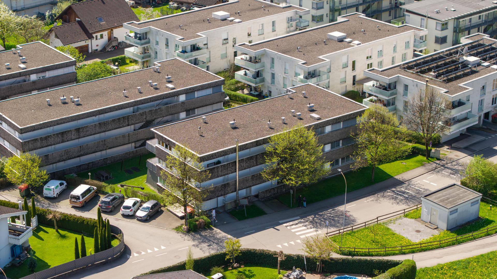 Übersichtliche Luftaufnahme einer Wohnsiedlung mit modernen Gebäuden und Parkplätzen.
