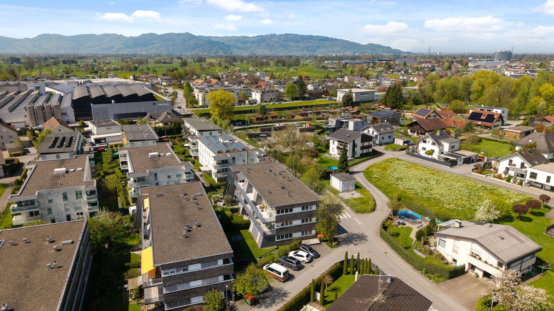 Panoramablick aus der Luft auf eine Wohngegend mit Bergen im Hintergrund.