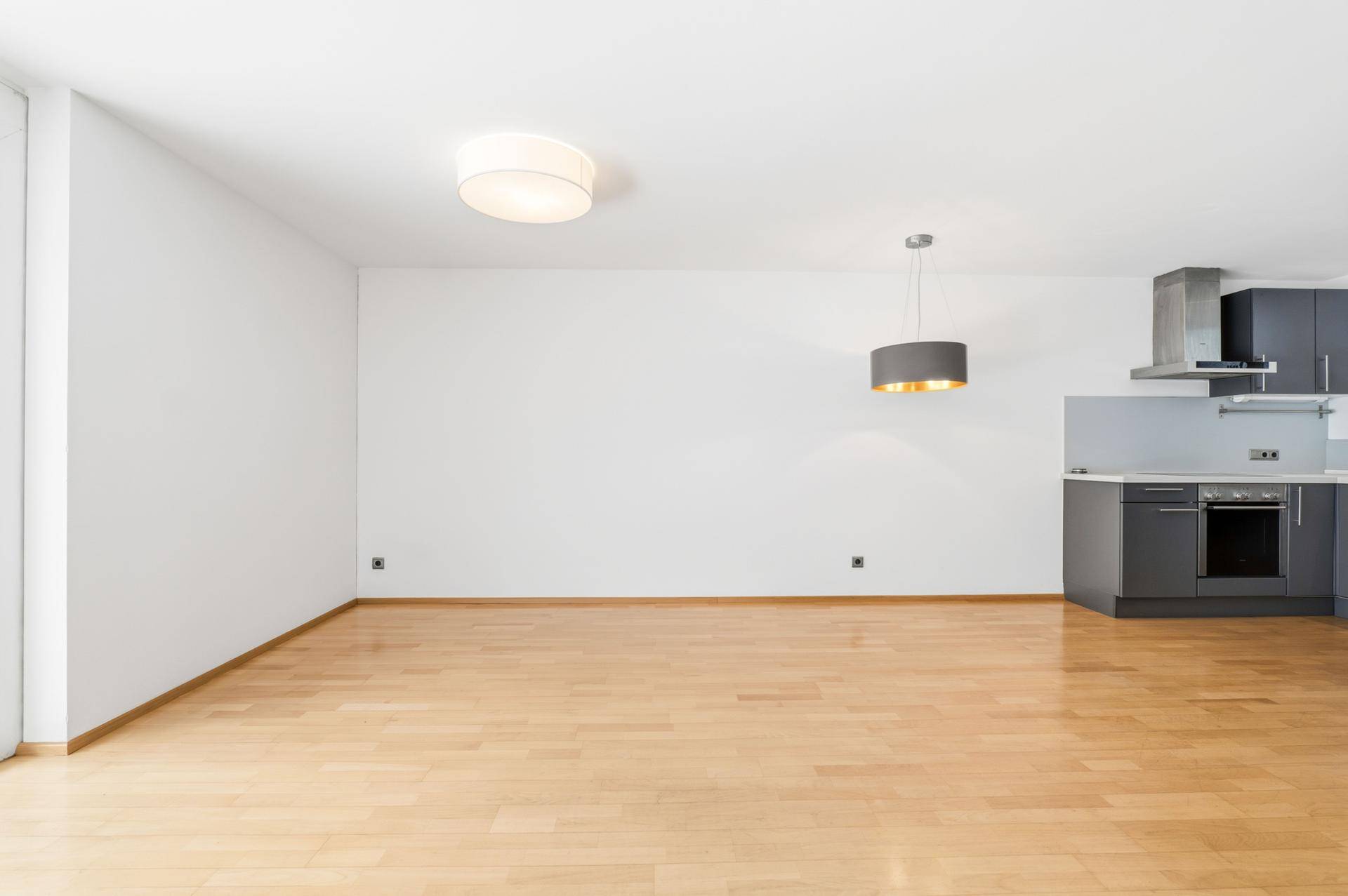Heller, offener Wohnbereich mit Parkettboden und moderner Küchenzeile im Hintergrund.