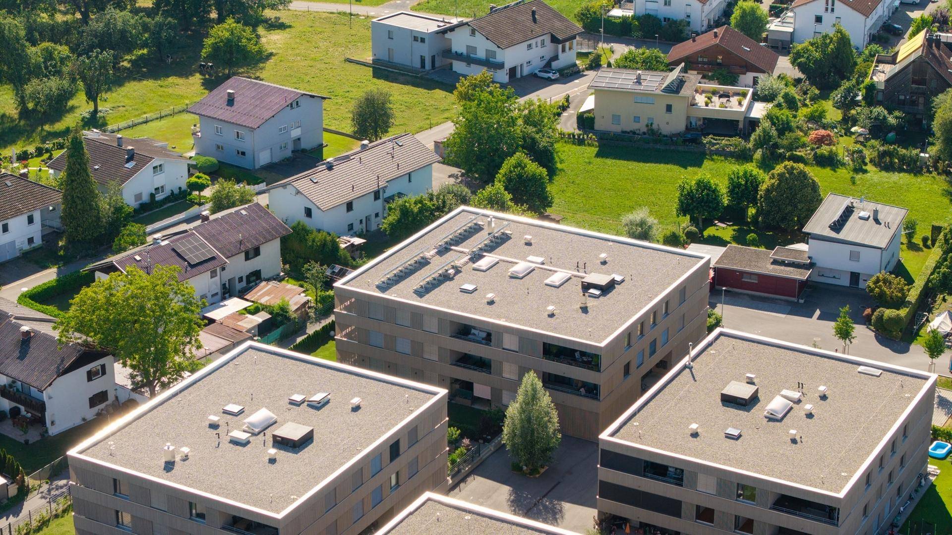 Luftaufnahme eines Wohngebiets mit modernen Gebäuden und umliegenden Häusern.