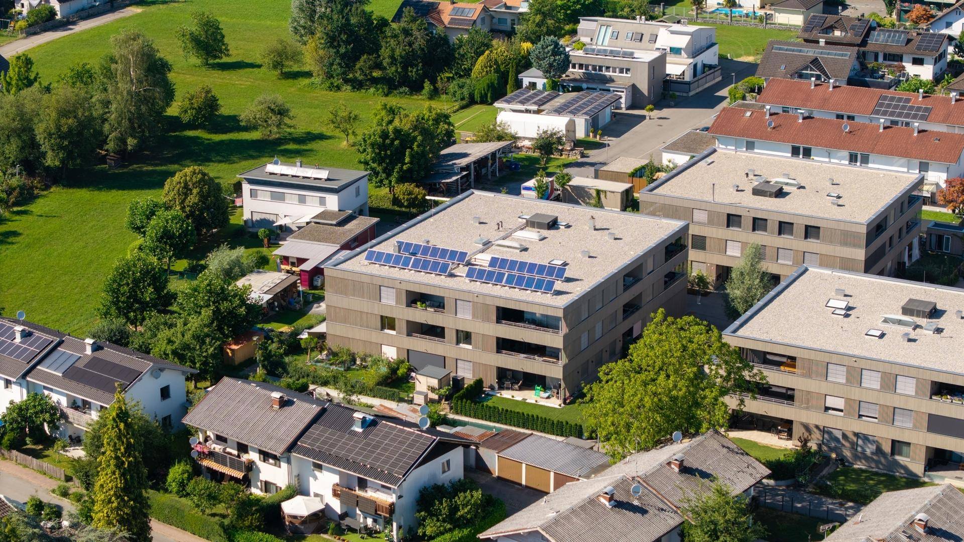 Luftaufnahme eines Wohngebiets mit modernen Gebäuden und viel Grünfläche.