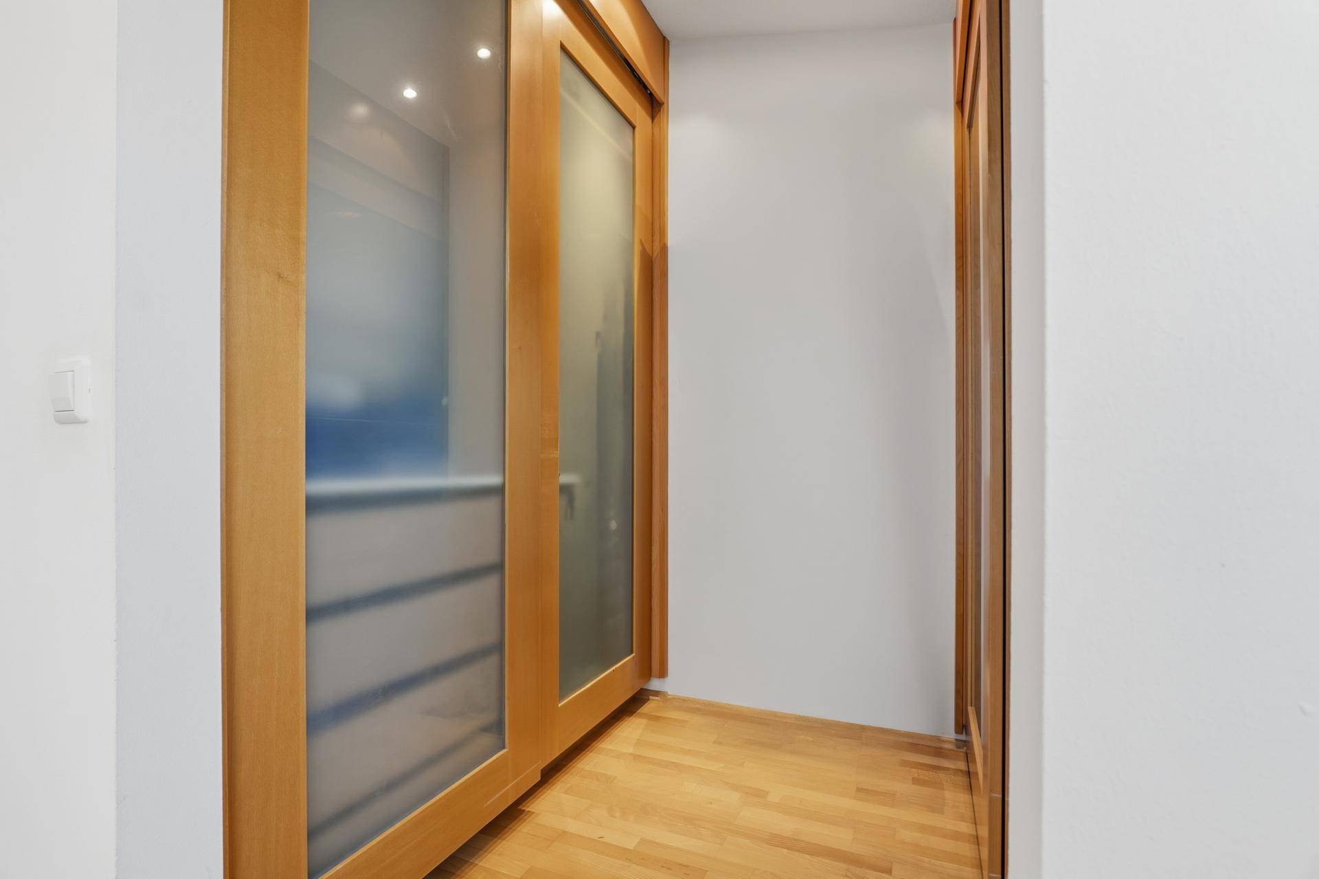 Praktischer begehbarer Kleiderschrank mit Schiebetüren aus Milchglas.