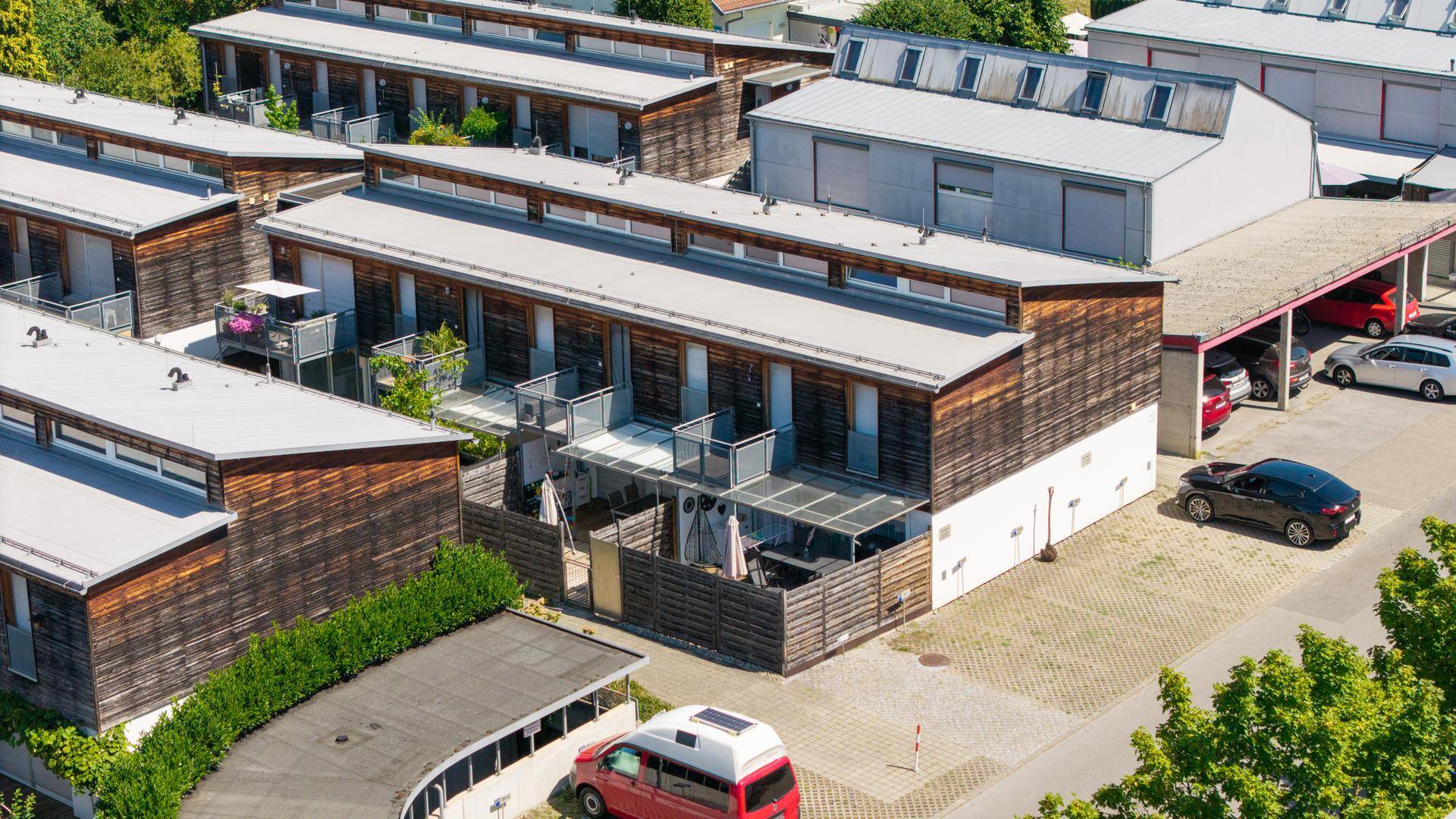 Detaillierte Luftaufnahme einer modernen Wohnanlage mit Holzfassaden und privaten Terrassenbereichen.
