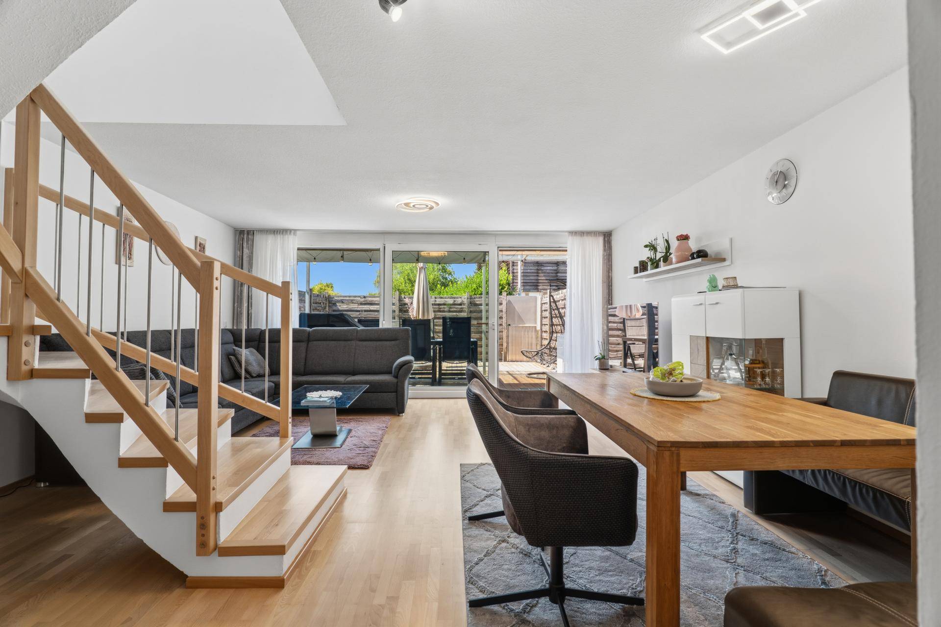Geräumiger Wohn- und Essbereich mit Zugang zur Terrasse und heller Holztreppe.