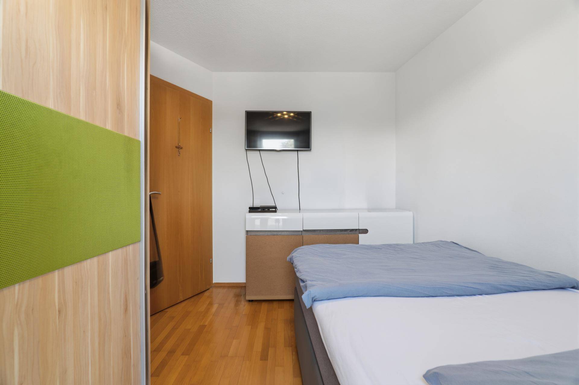 Kinderzimmer mit Einzelbett, Fernseher und praktischem Kleiderschrank.