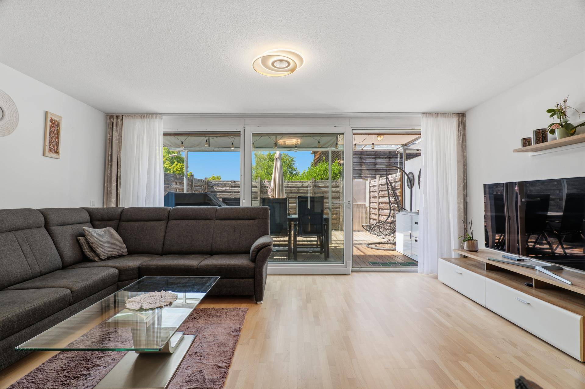 Gemütliches Wohnzimmer mit großem Sofa und breiten Schiebetüren zur Außenterrasse.