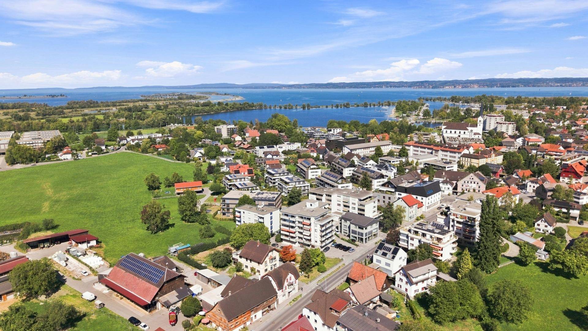 Luftaufnahme einer Stadt mit Wohngebäuden, Grünflächen und einem großen See, attraktive Lage.