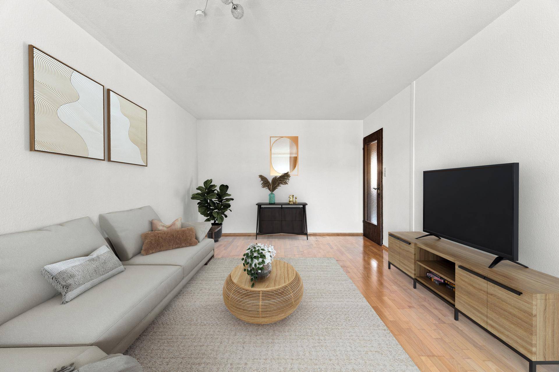 Modern eingerichtetes Wohnzimmer mit hellem Sofa, Holzboden und dekorativen Bildern an der Wand.