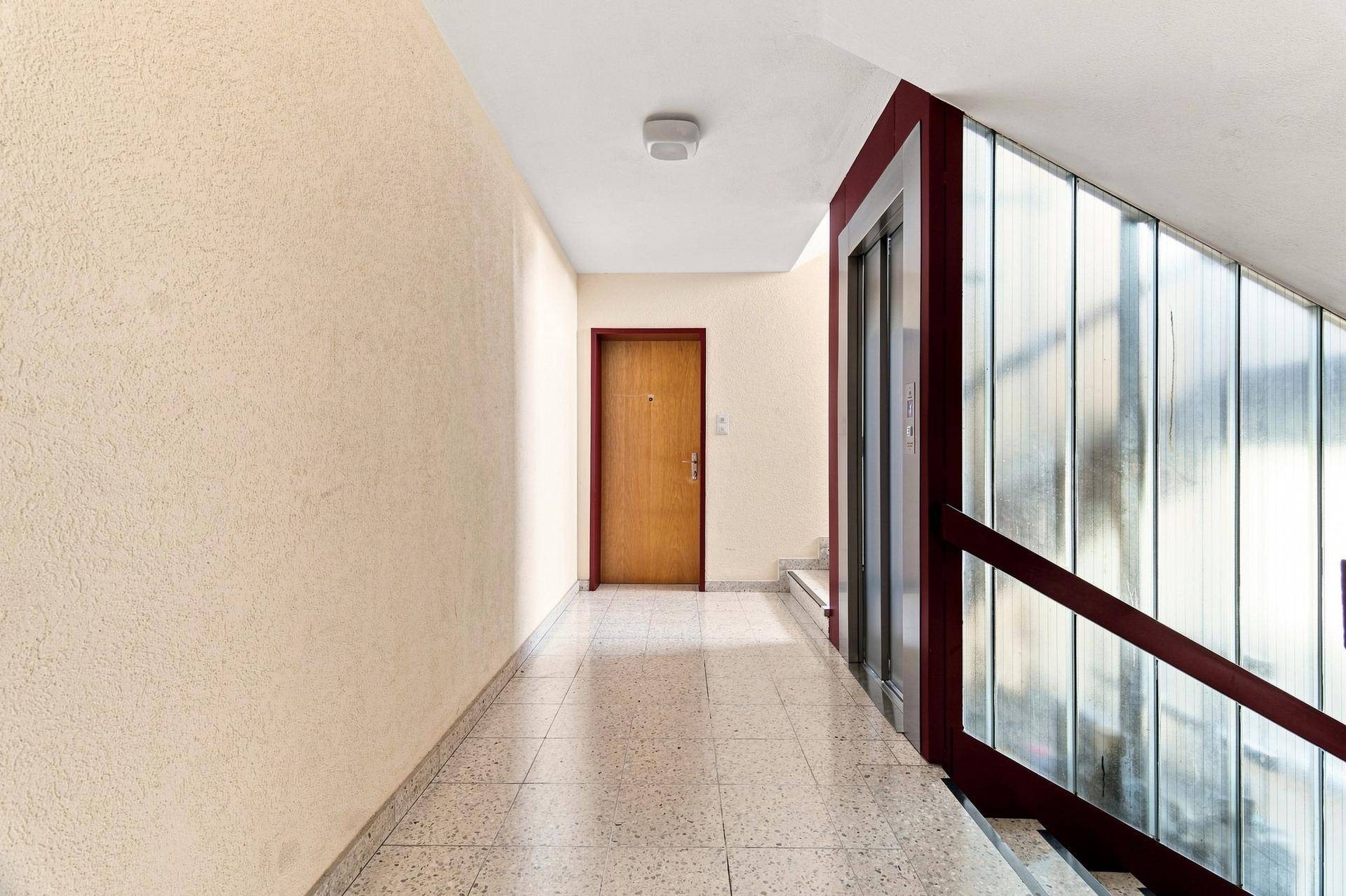 Heller Hausflur mit Aufzug und Treppenhaus, ausgestattet mit Fliesenboden, gut gepflegt.