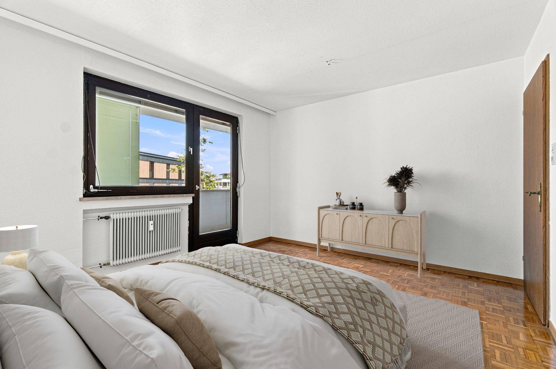 Helles Schlafzimmer mit Parkettboden, modernem Bett und Kommode, sowie Balkontür für frische Luft.