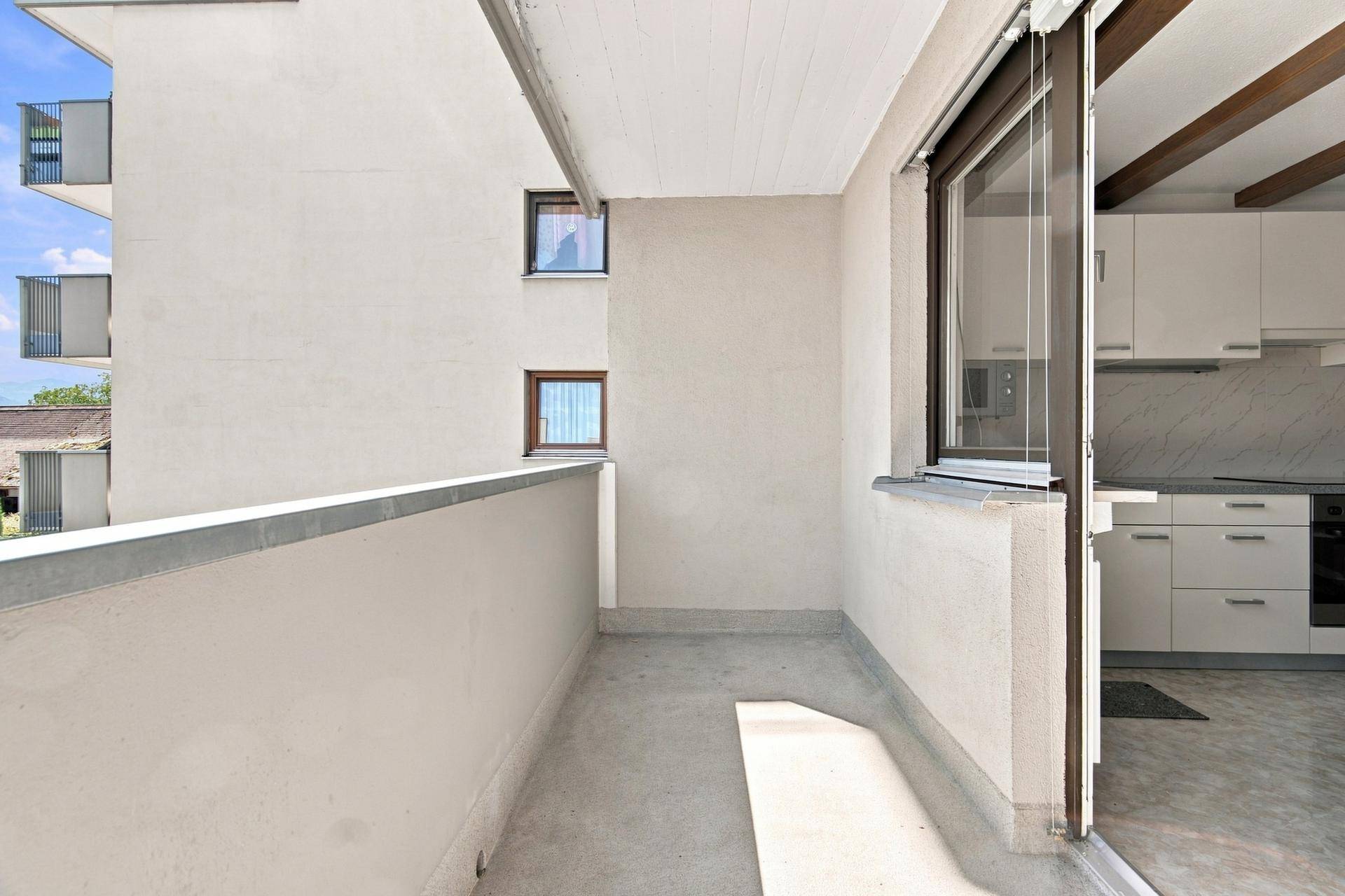 Heller Balkon mit Blick auf die Umgebung und direktem Zugang zur Küche, ideal für Mahlzeiten im Freien.
