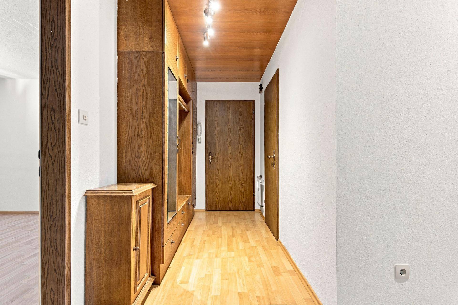 Langer Flur mit Holzboden, Holzdecke und praktischen Einbauschränken aus Holz, funktional und stilvoll.