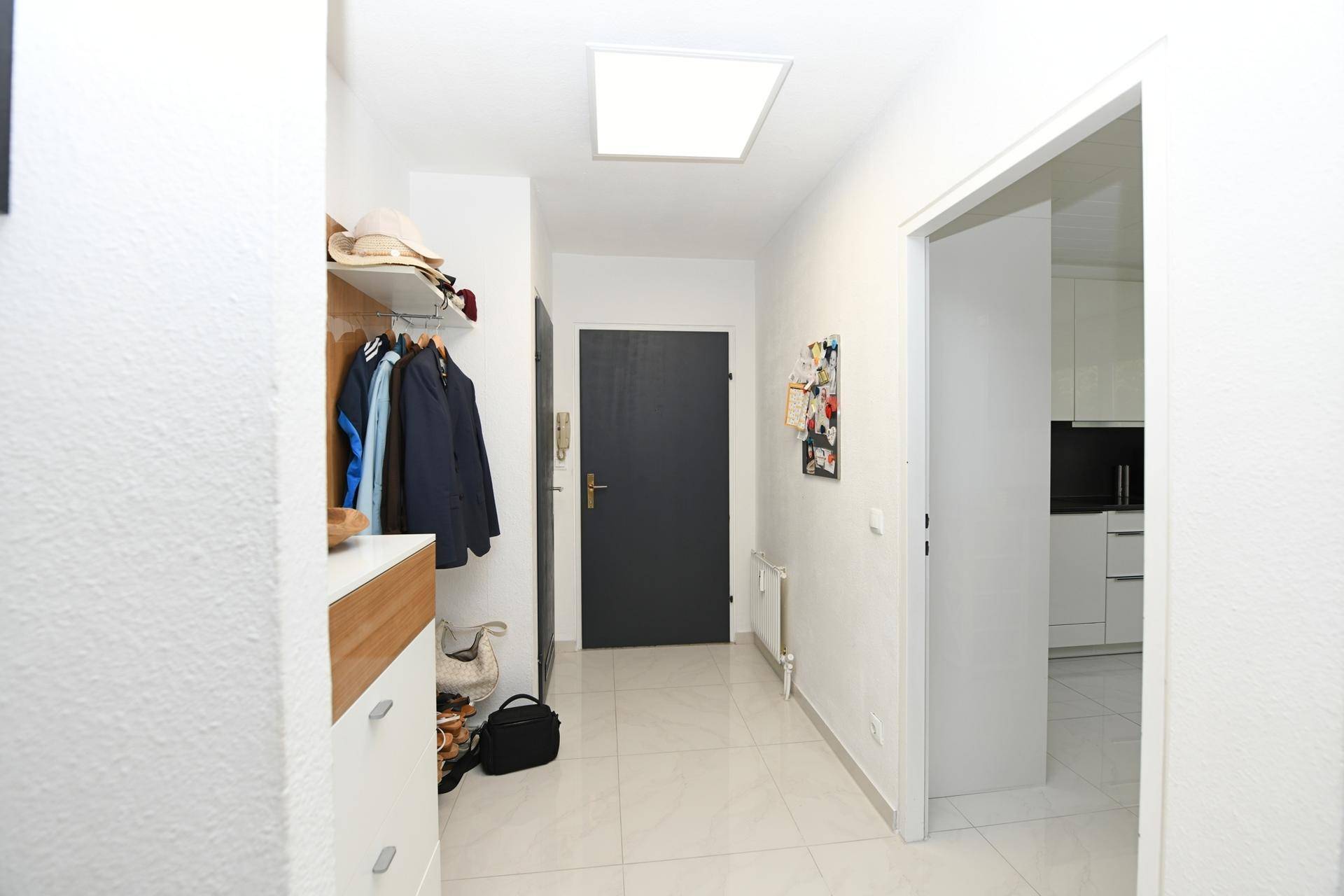 Heller Flur mit Garderobe, Schuhschrank und modernen Fliesen.